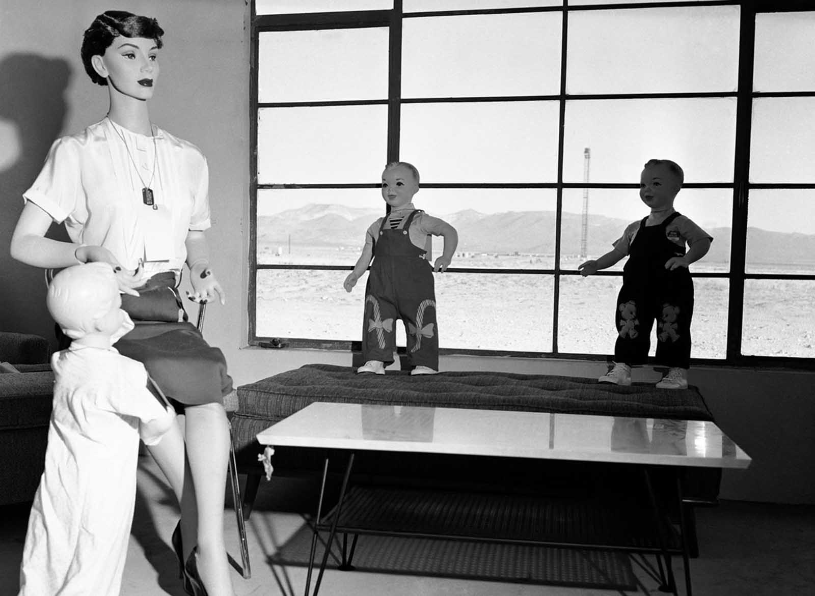 Mannequins that represent a typical American family will soon experience the fury of an atomic blast with the power of 40,000 tons of TNT at Yucca Flat, Nevada, on April, 24, 1955. The test is being conducted to determine the survival chances of an atomic attack. Visible through the window is the tower 4,700 feet away on which the detonation will occur.