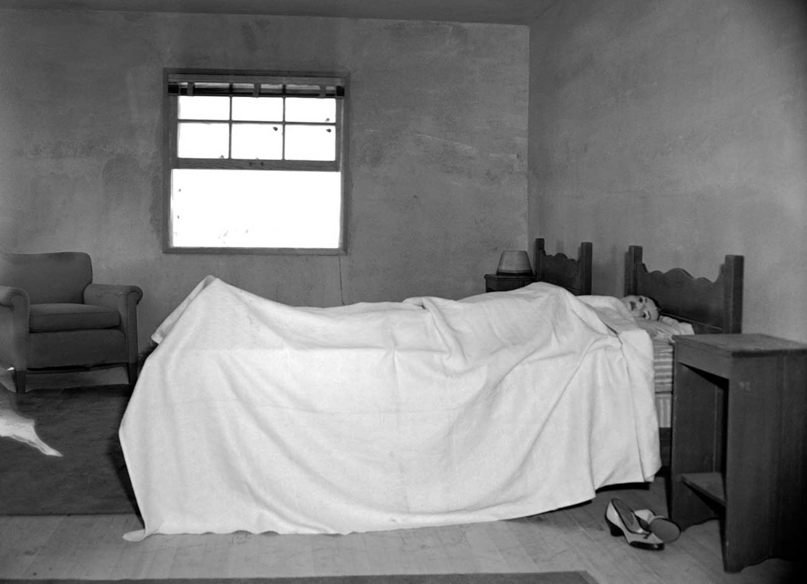 (1 of 2) Stretched on a bed, in an upstairs bedroom of House No. 2, is a mannequin ready to test the effects of an atomic explosion at the atomic proving grounds near Las Vegas, Nevada, March 15, 1953. Through the window a mile and a half away stands a 300-foot steel tower atop which the bomb will be detonated. The purpose of the test blast is to show Civil Defense officials what would happen in an American city if it were subjected to a atomic attack.
