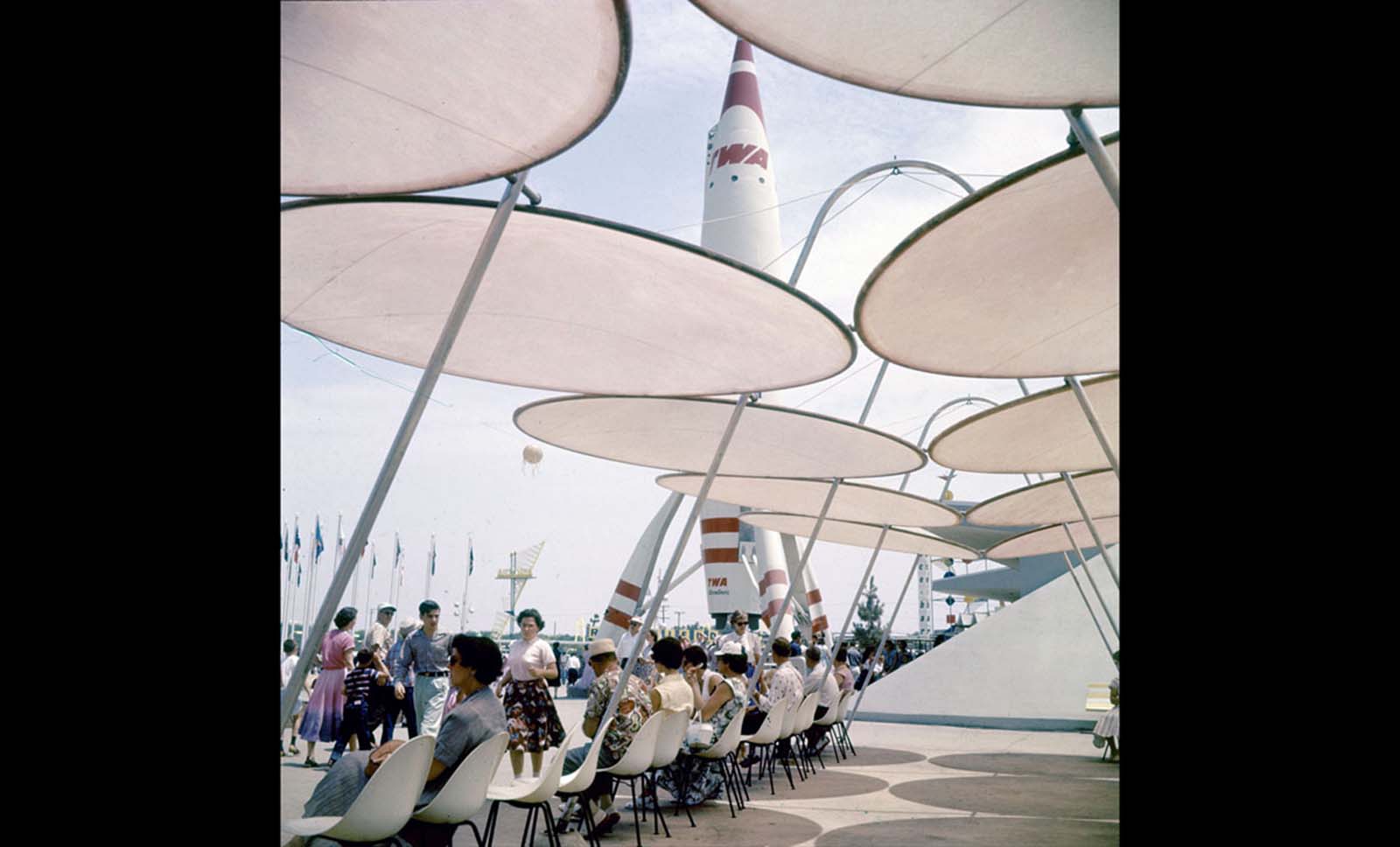 Park attendees relax under sunshades near a TWA rocket in Disneyland in July 1955.