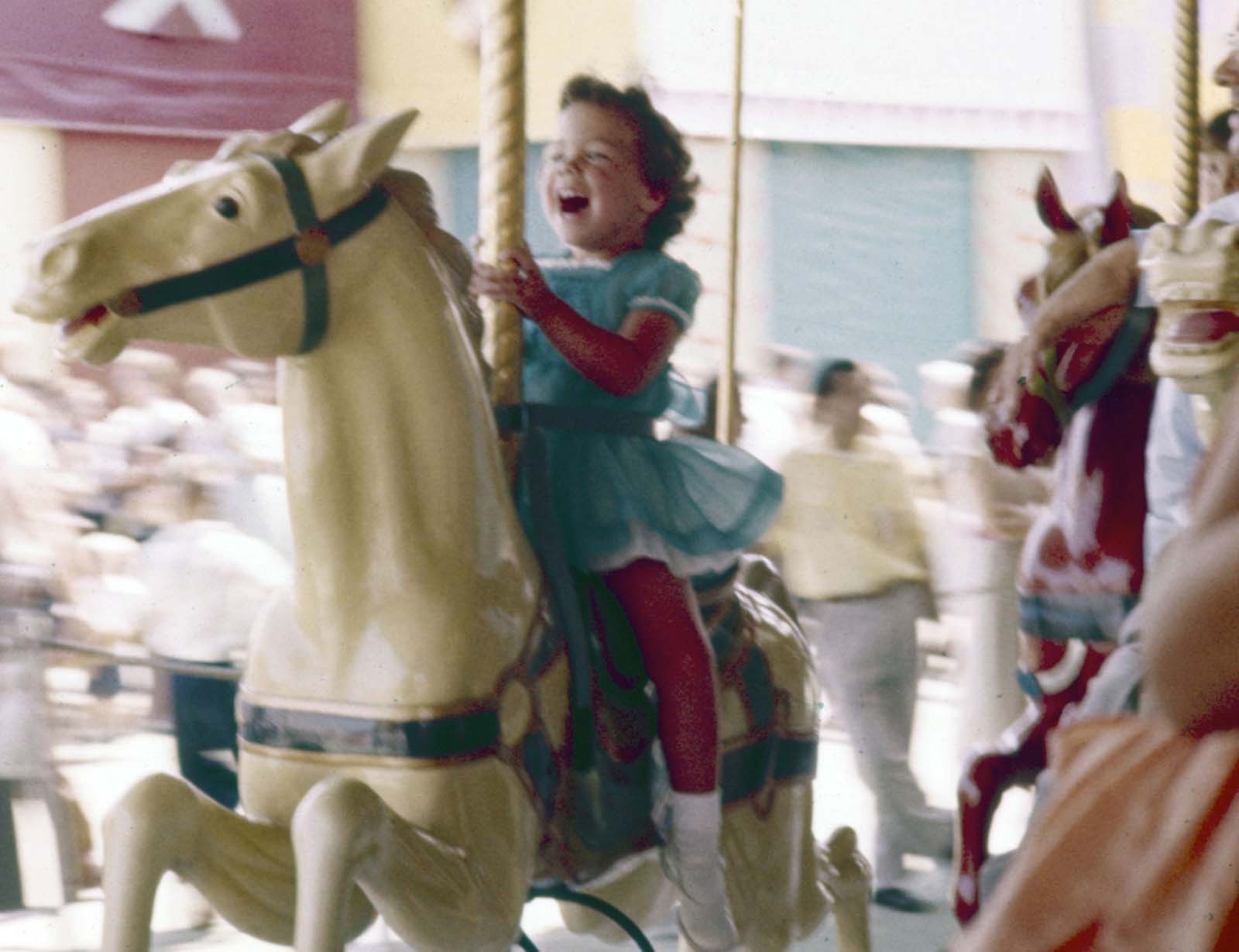 A little girl laughs with excitement while riding a carousel at Disneyland in July 1955.