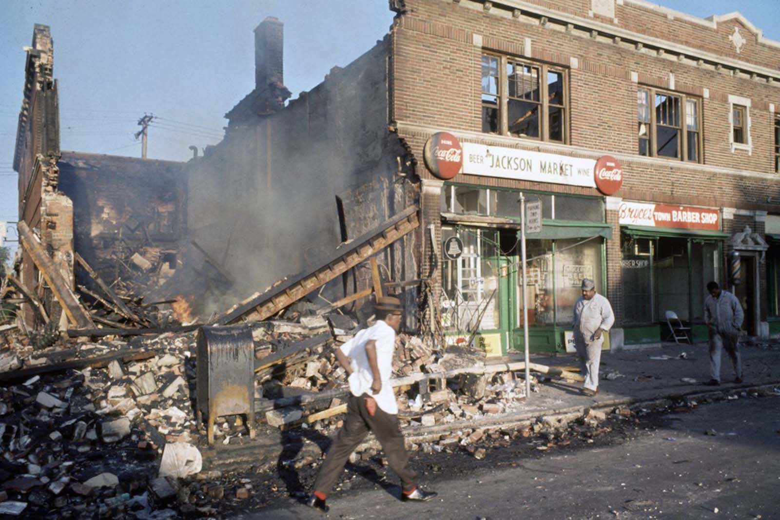 People walk by a destroyed building.