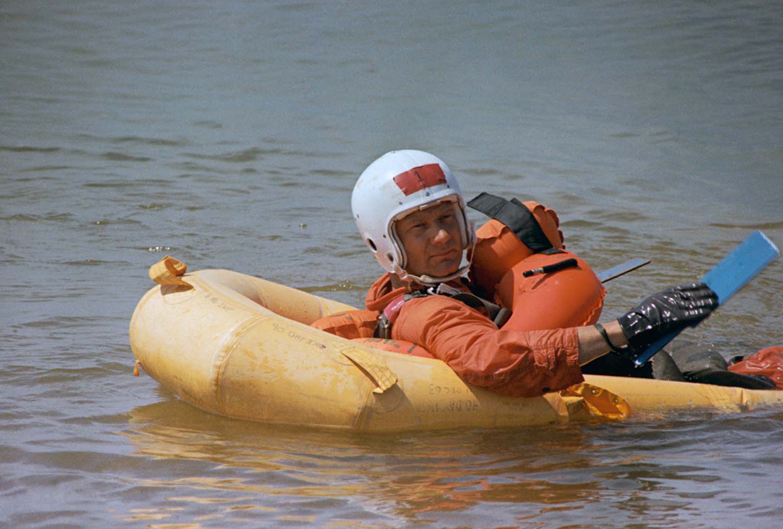 The astronaut Buzz Aldrin paddles to the shore of Lake Texoma during training at the U.S. Air Force Air Defense Command Life Support School at Perrin Air Force Base in Sherman, Texas. He sits in a one-man life raft. He was dropped into the water after making a parasail ascent some 400 feet above the lake.