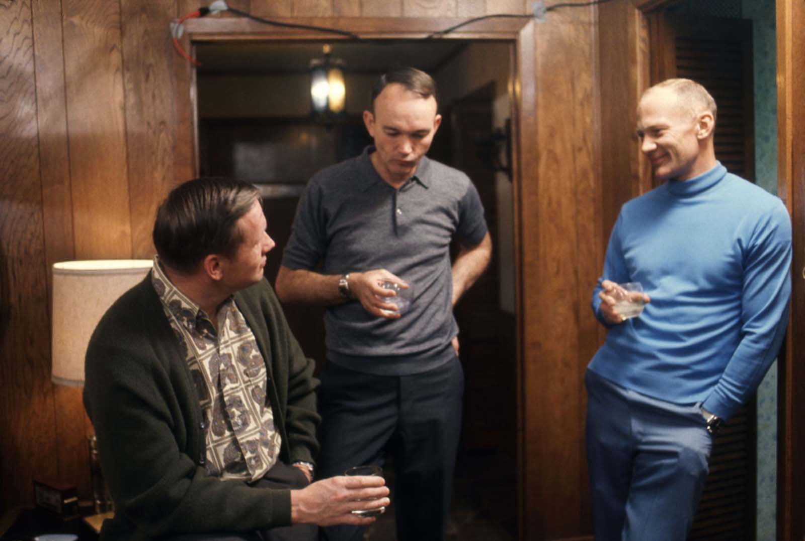 From left: The astronauts Neil Armstrong, Michael Collins, and Buzz Aldrin talk over drinks in a wood-paneled room in Houston, Texas, in March 1969.