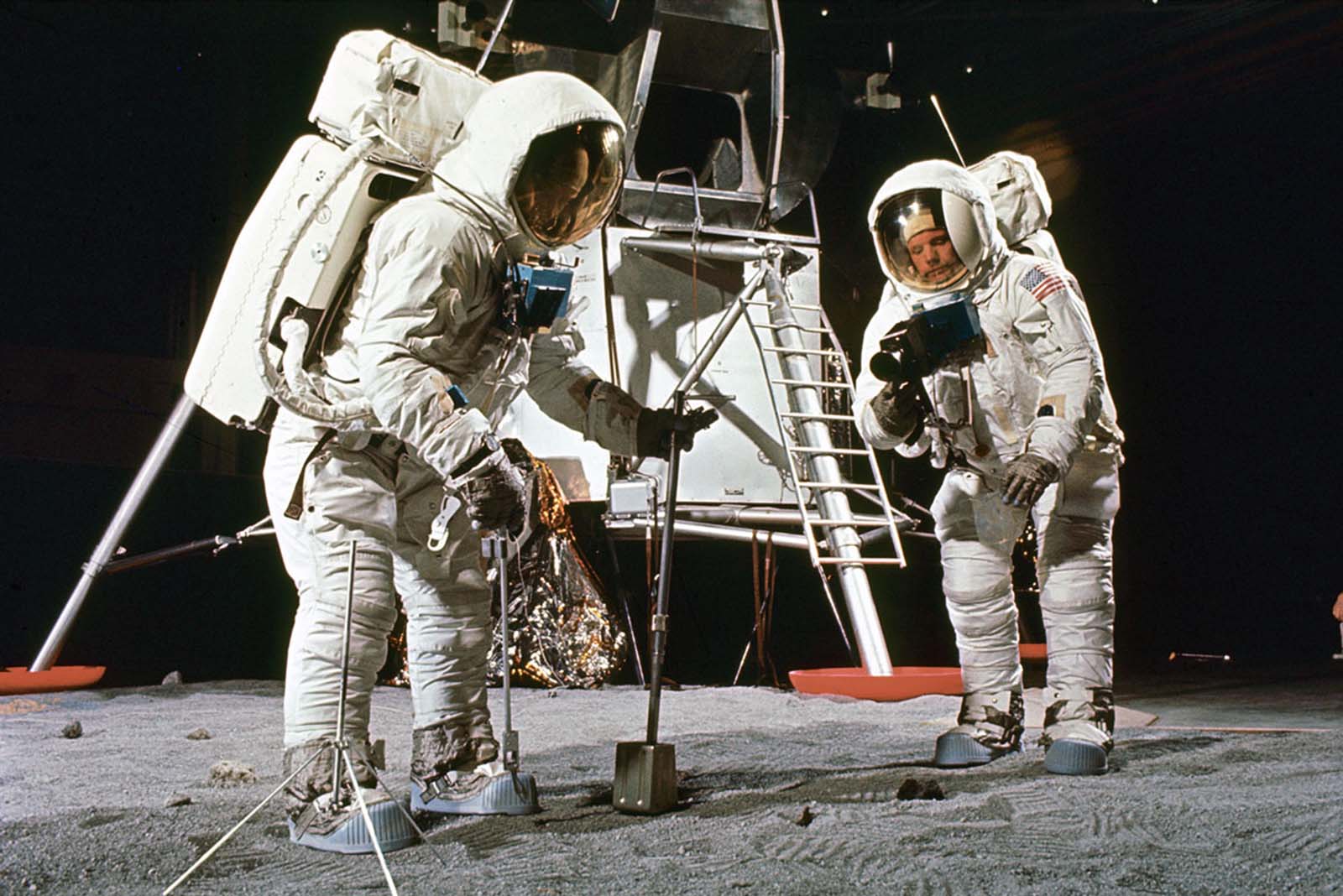 Buzz Aldrin (left) and Neil Armstrong train to make documented sample retrievals, suited up near a mock-up of the lunar lander in the spring of 1969.