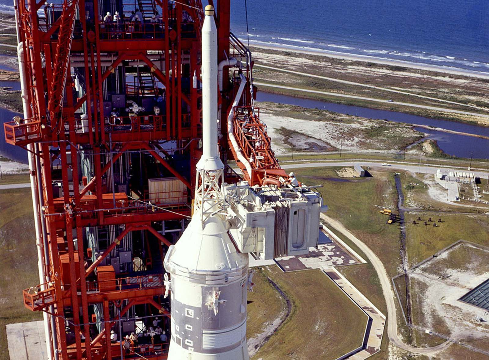 Readying for launch, a technician works atop the white room, through which the astronauts will enter the spacecraft, alongside the 363-foot (111-meter) Saturn V rocket standing on the launchpad at Kennedy Space Center.