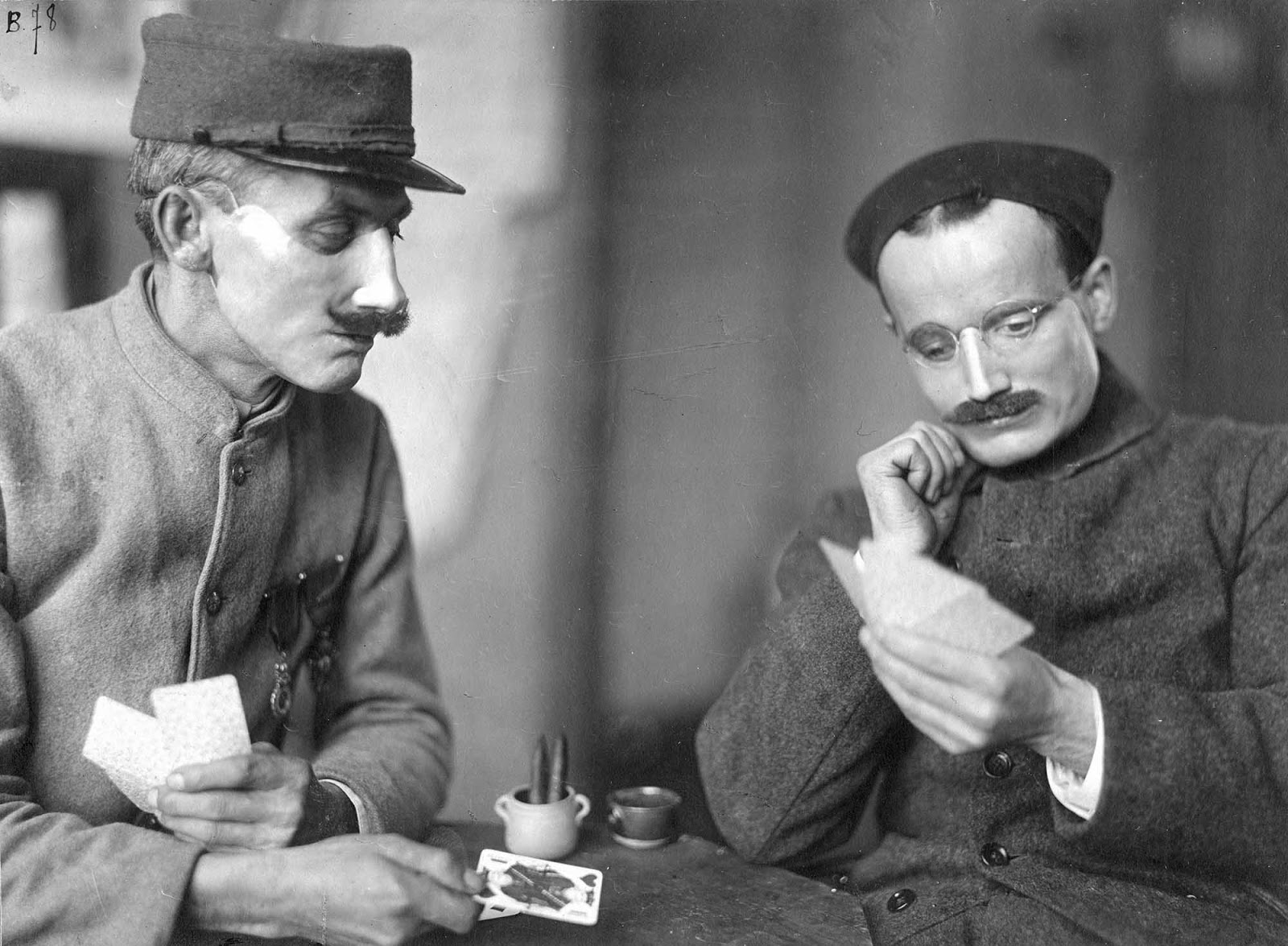 Two soldiers play cards while wearing Ladd's handiwork.