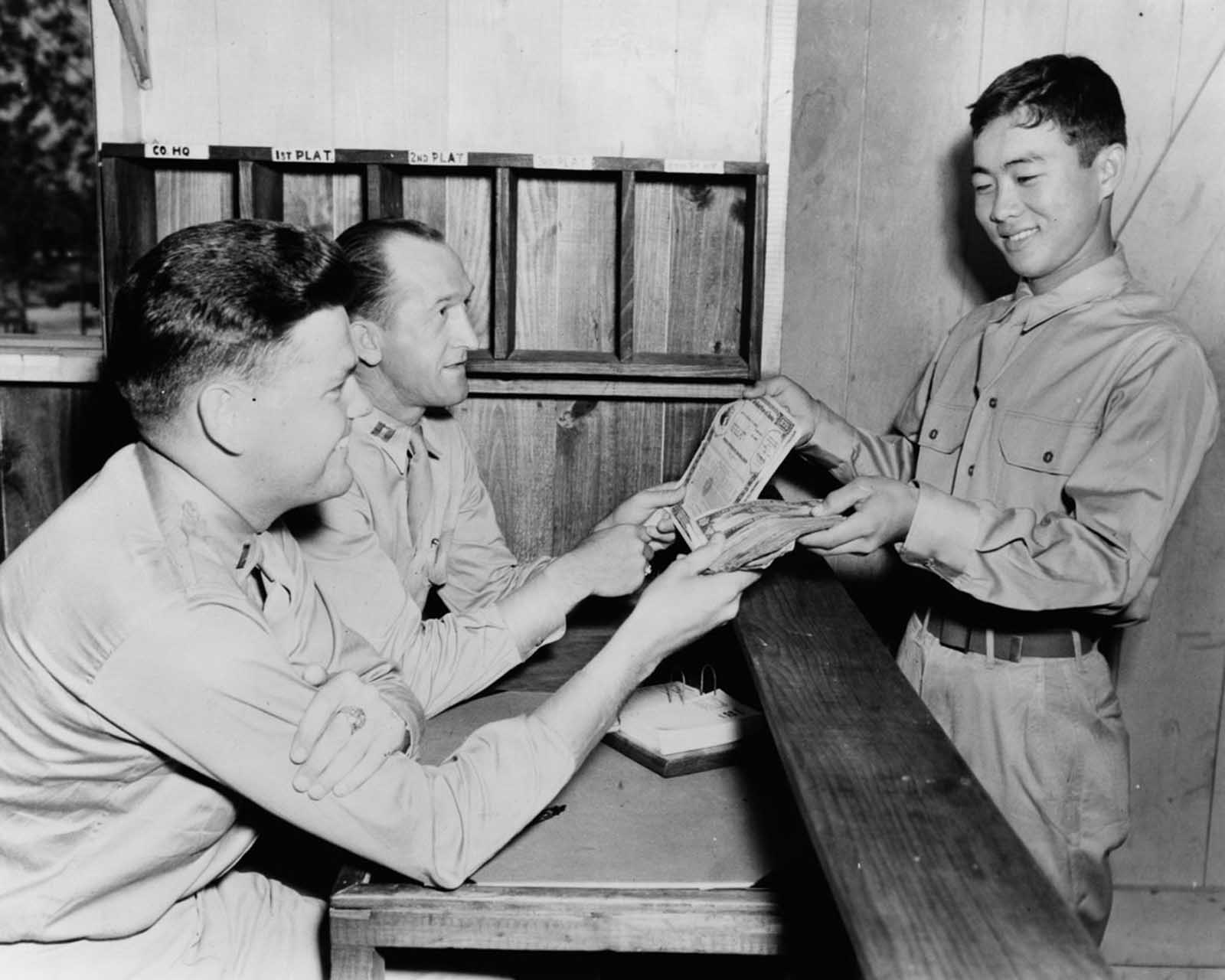 Private Jack Y. Oato purchases $2,500 worth of war bonds from his company commander. June, 1943.