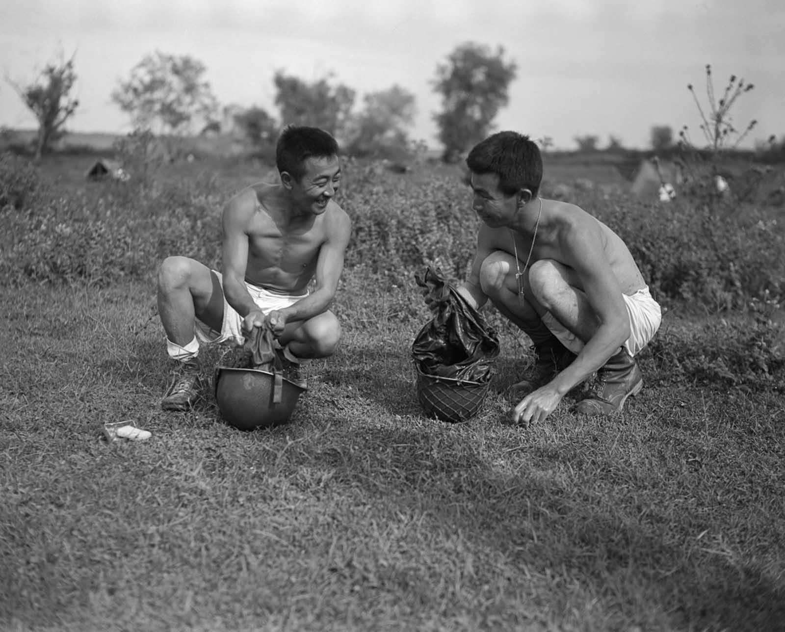 Shiro Yamato and Ginchi Masumotoya wash their uniforms in their helmets behind the lines during the invasion of Italy. October, 1943.