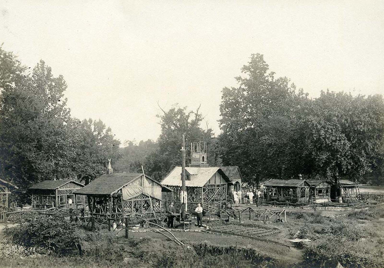 View of houses, gardens, a partially- constructed church, and German campers posing for a photograph in the German internment camp.