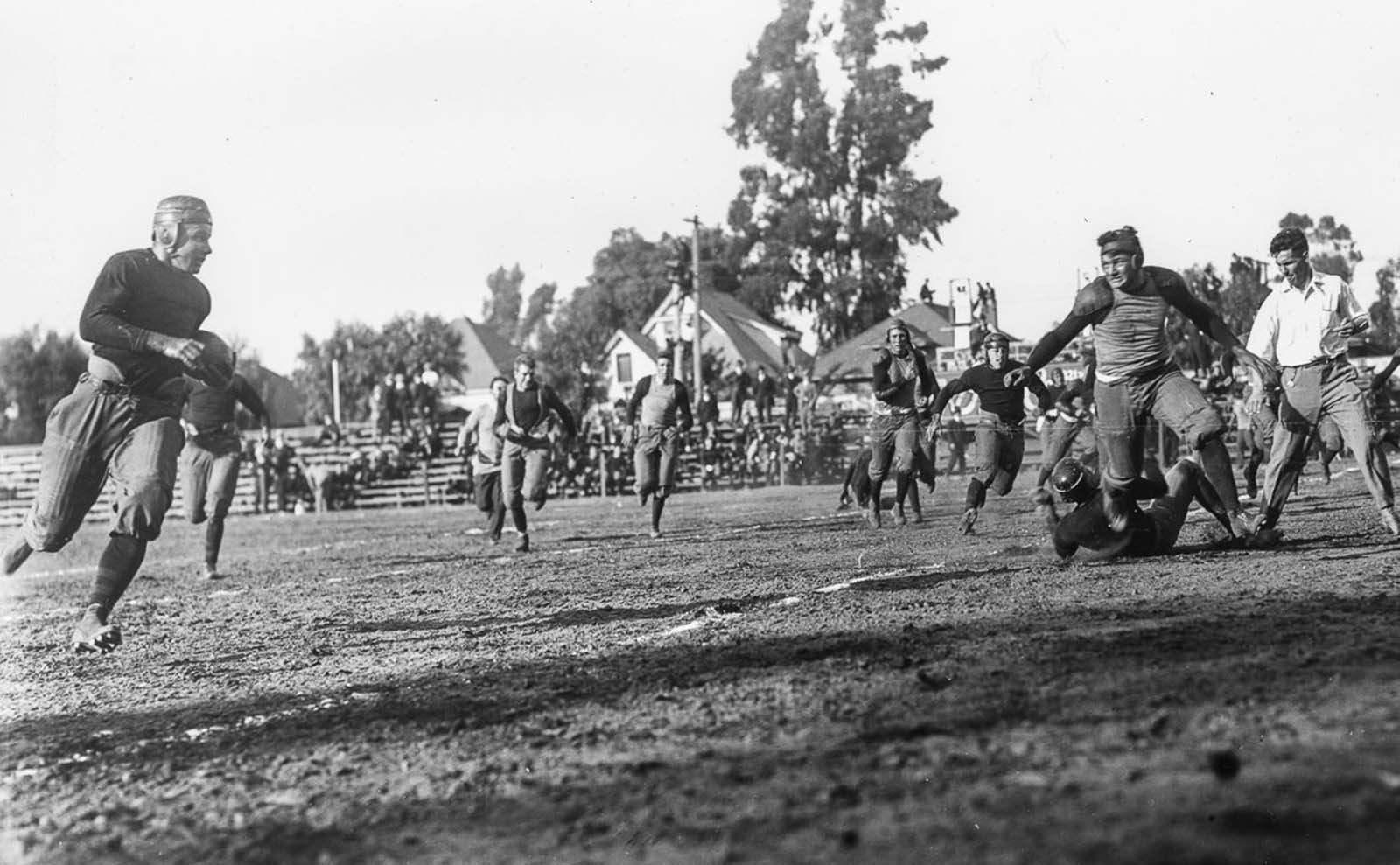 The University of Southern California Trojans football team run up field to make the play against the Saint Mary's College Gaels at the Los Angeles Memorial Coliseum. 1915.