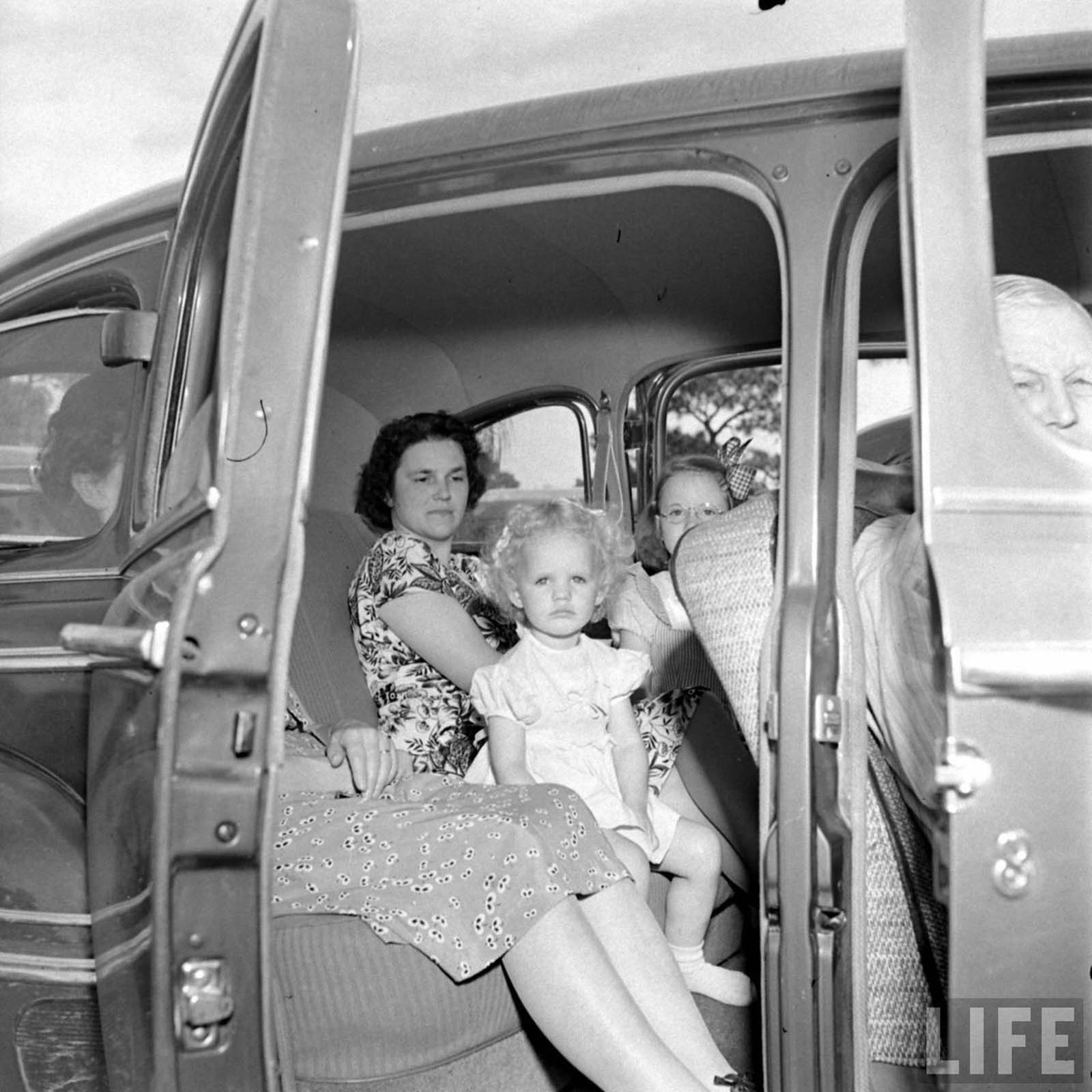 A family being comfortable in their own car while attending the church.