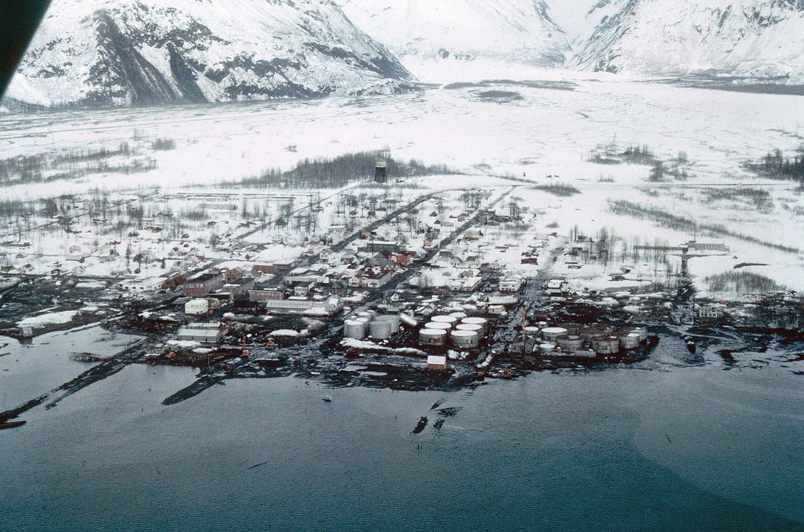 A view of the destruction of Valdez, Alaska. Thirty-one residents died during the earthquake and subsequent tsunami. Instability and vulnerability to future tsunamis made the old town site too dangerous to rebuild, so the town was relocated several miles west to more stable ground, and rebuilt.