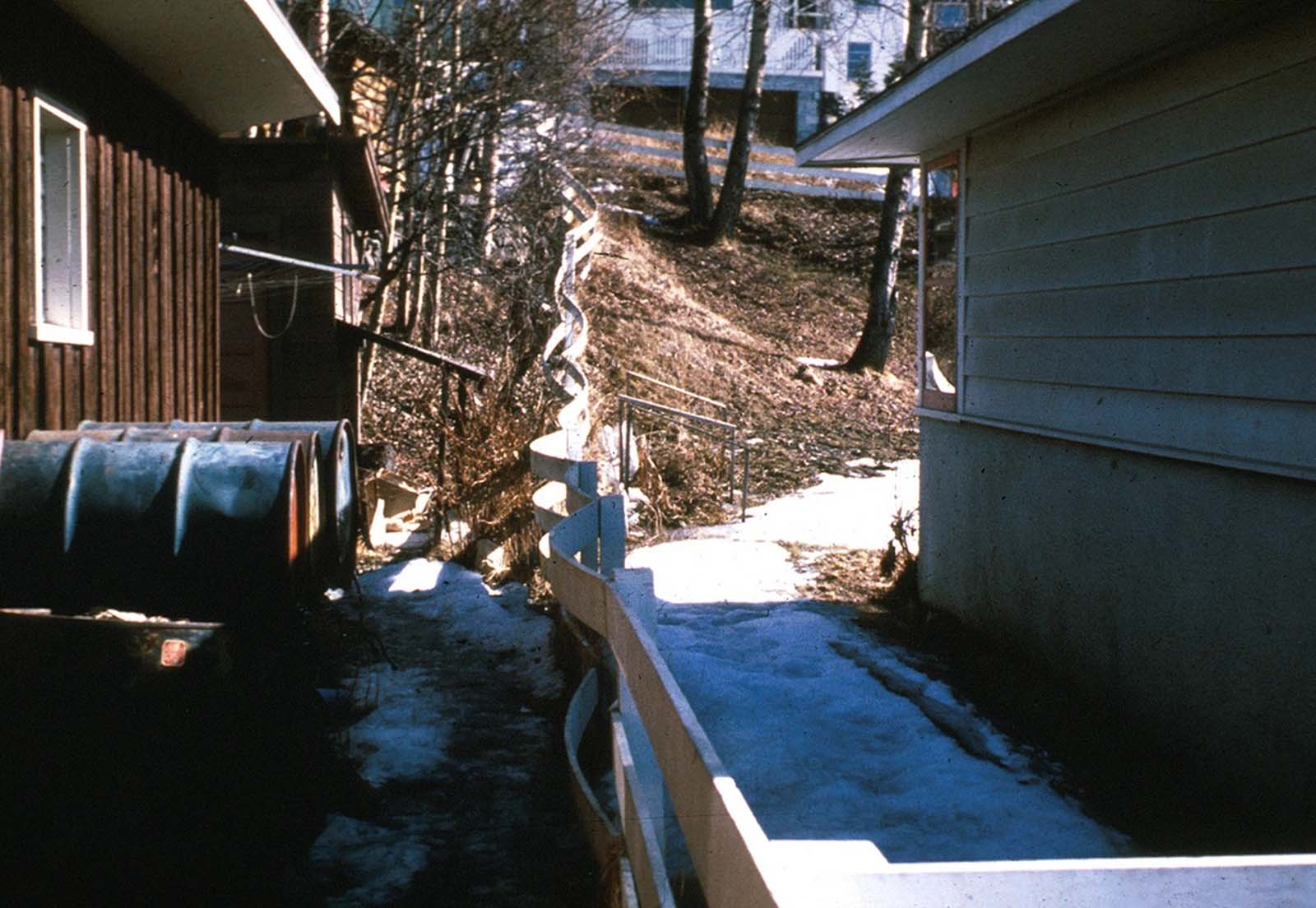 In an Anchorage neighborhood, a wooden fence at the toe of the L Street landslide, buckled and shortened by compression.