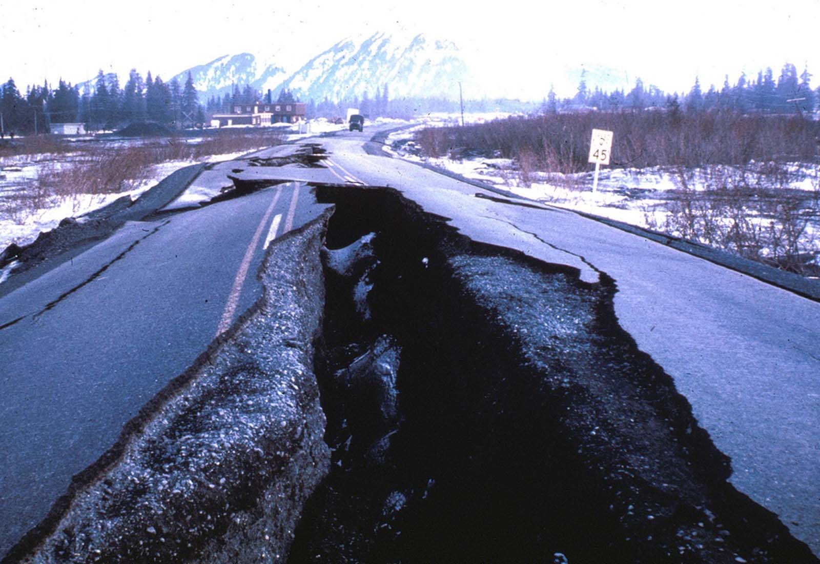 This highway embankment fissured and spread, cracking down the middle. The road was built on thick deposits of alluvium and tidal estuary mud along Turnagain Arm near Portage.