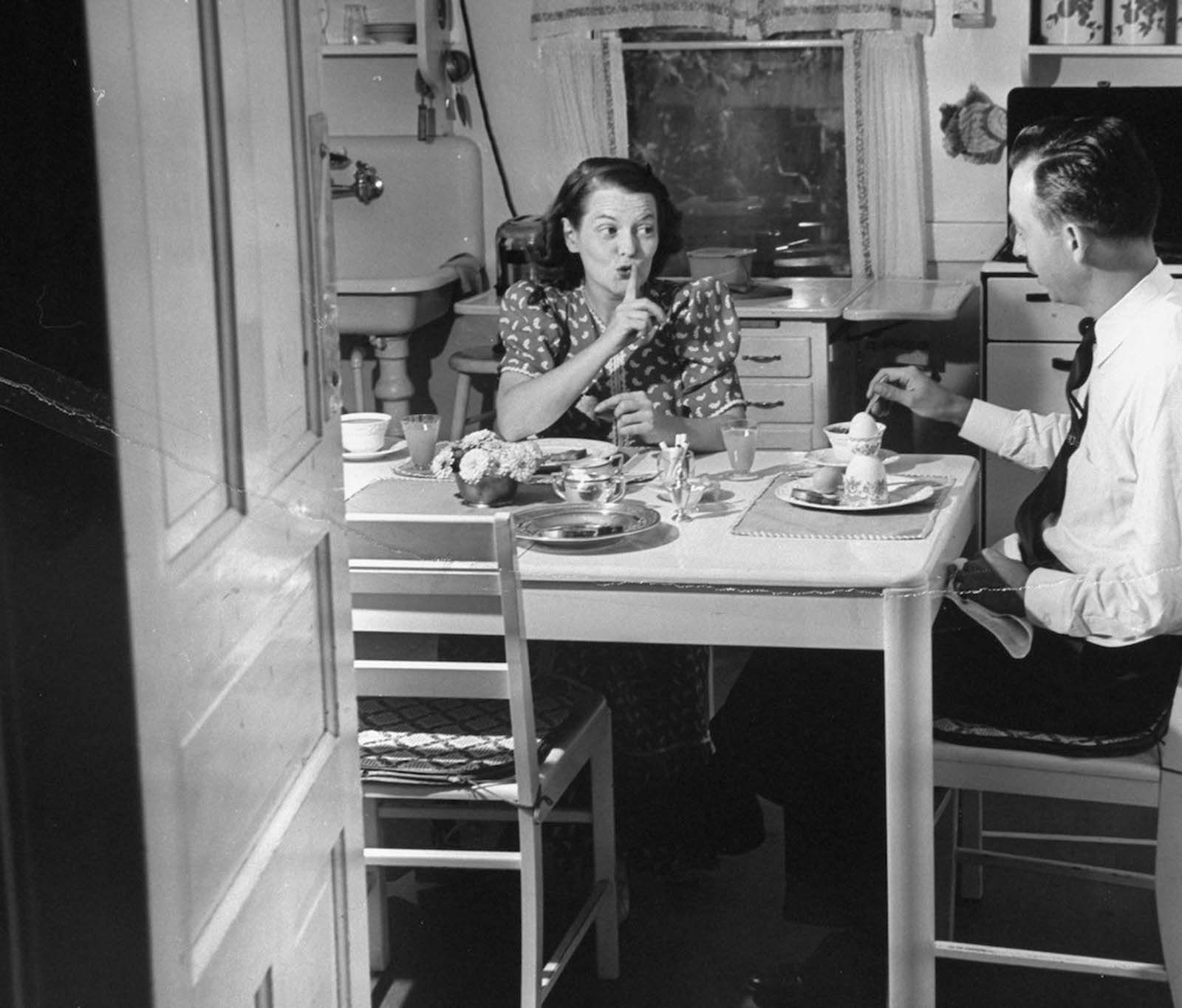 Jane shushing her husband Gilbert, as they sit having a quiet 6:30 a.m. breakfast before their three kids wake up, in the kitchen at their home.