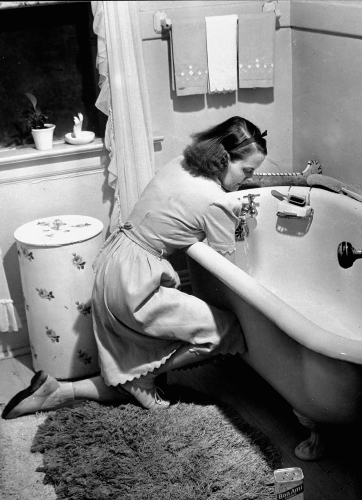 Jane scrubbing the bathtub in bathroom at home.
