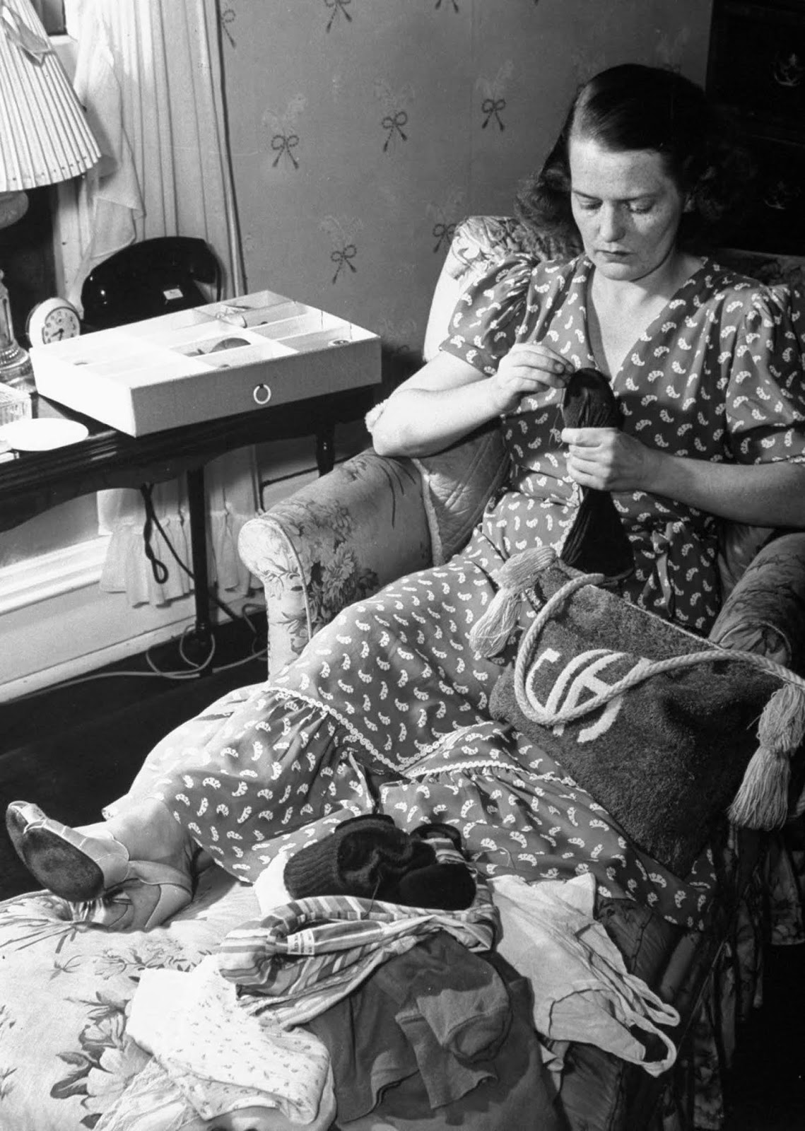 Jane mending a pair of socks as she lounges in bedroom while listening to her favorite jazz records during her leisure hours (time with out kids).