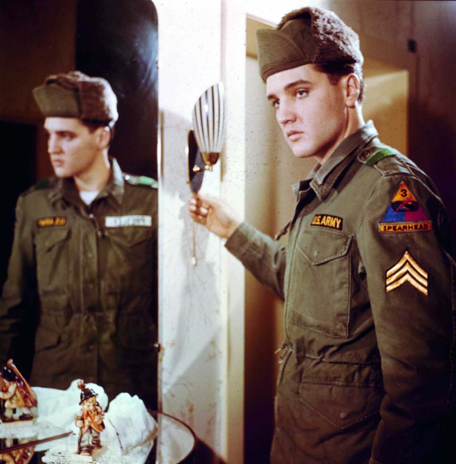 Elvis poses for a portrait next to a mirror during his tour of duty in Germany.