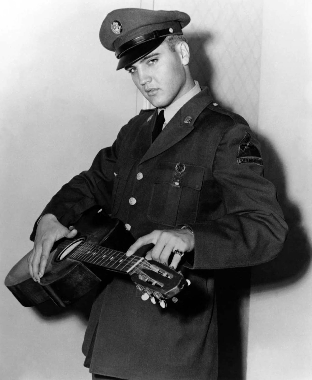 Presley the soldier poses with his guitar.