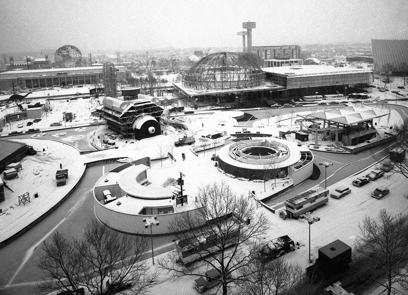 A mantle of snow covers the construction site of the 1964 World's Fair in New York City on February 19, 1964. In the foreground is the Chrysler Motors Exhibit, backed by the skeleton dome of the Travel and Transportation Pavilion. At far left is the New York City building, with the fair's symbol, the Unisphere, behind it.