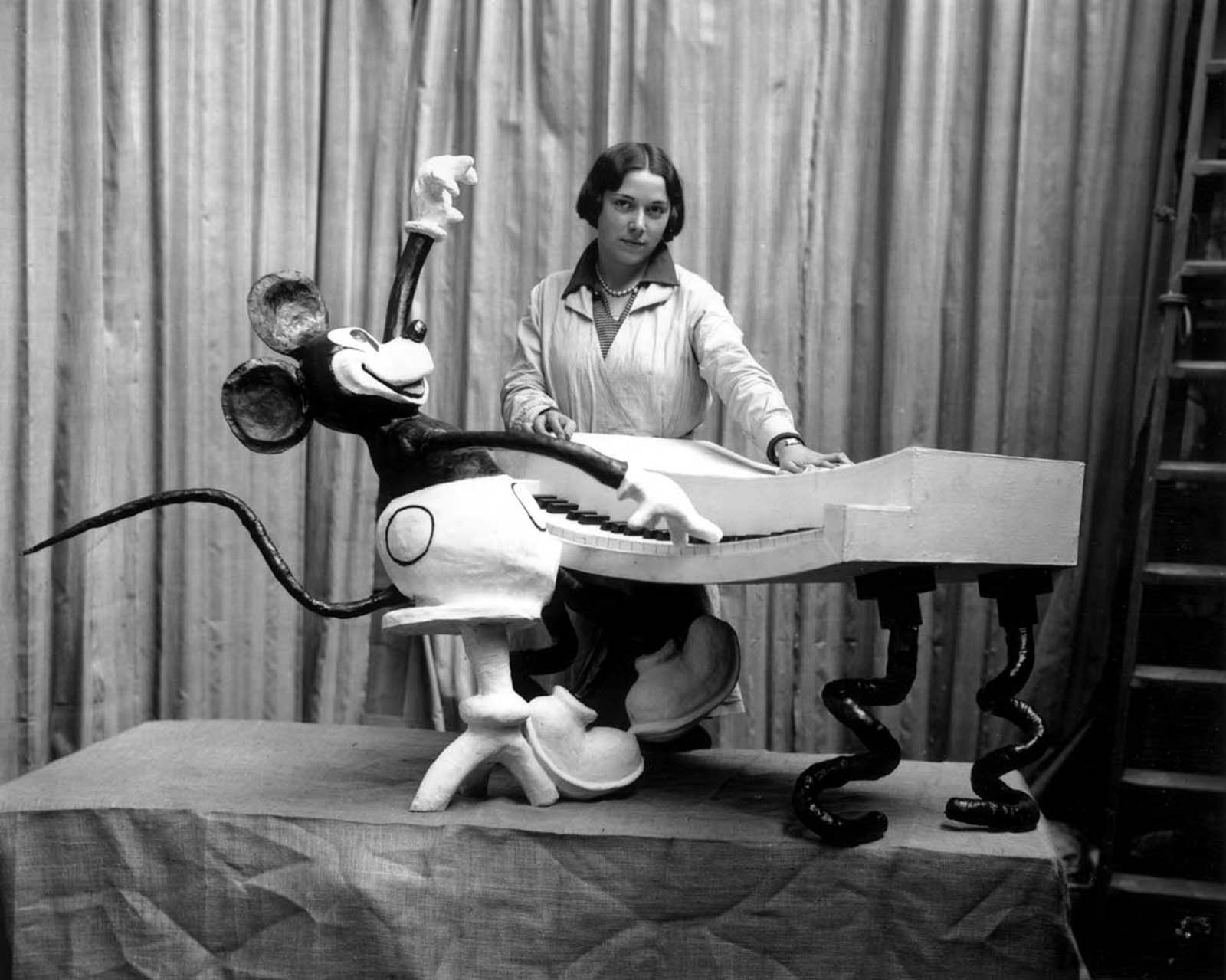 An employee at Madame Tussaud’s waxworks museum on Marylebone Road, London, putting the finishing touches to a waxwork of Mickey Mouse at the keyboard. 1930.