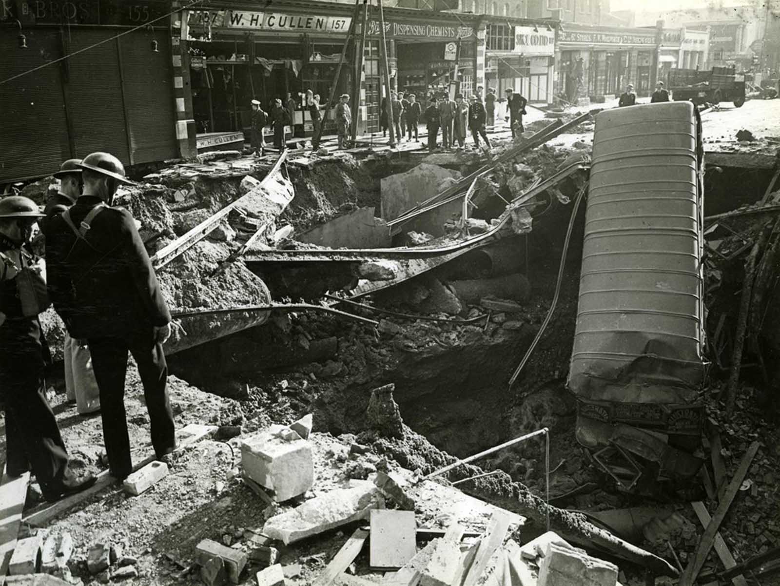 Sections of tram track are also visible among the debris. Workmen and others stand around the rim of the crater.