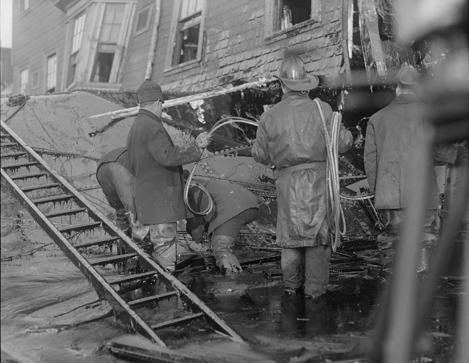 Firemen standing in thick molasses after the disaster. Muck drips off the ladder's rungs.