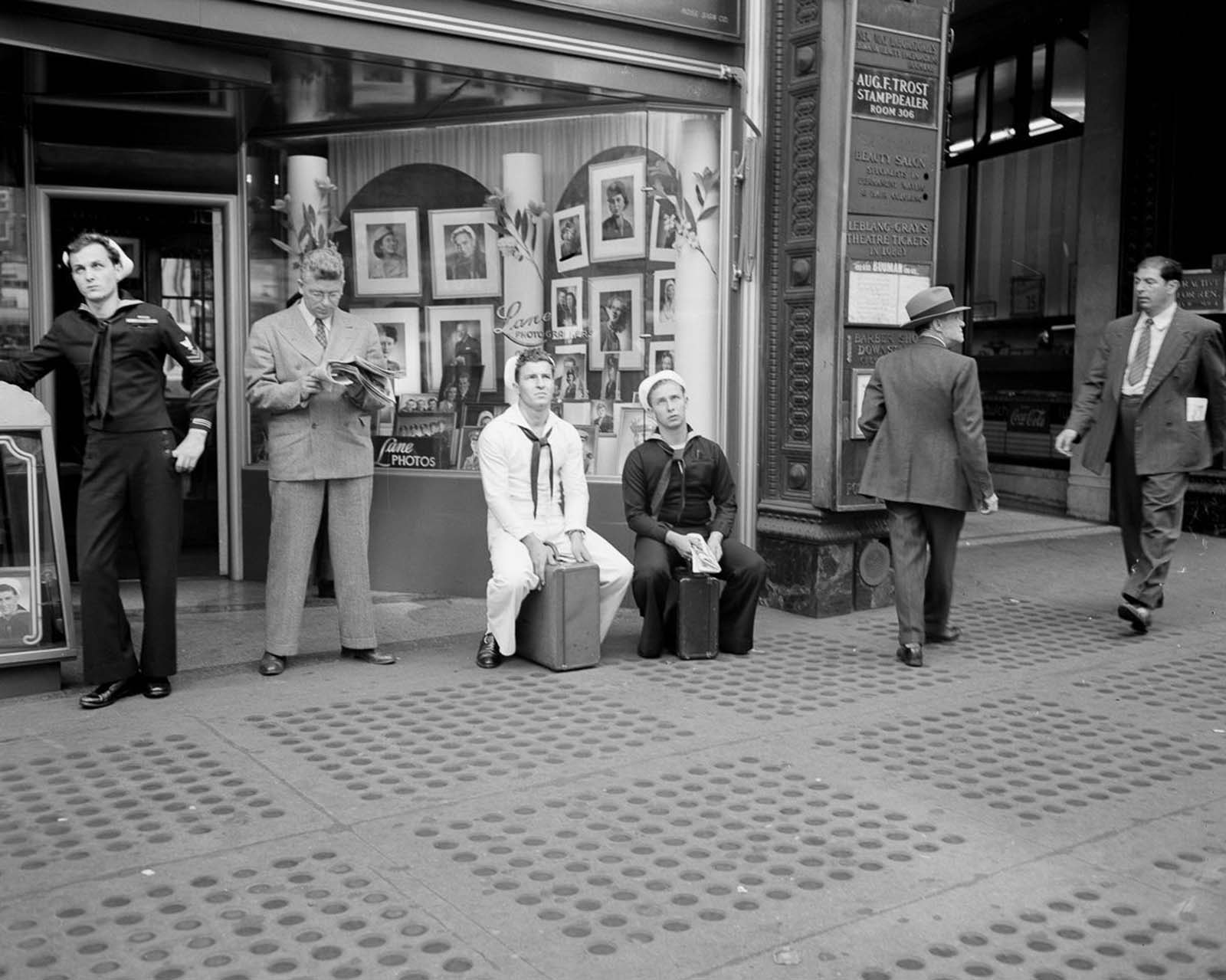 Sailors sit on their briefcases and lean against door frames as they wait for more news in one of the most significant developments of World War Two.