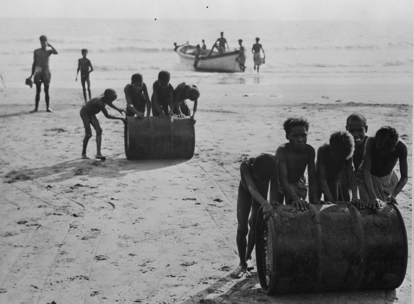 Boys help unload fuel drums during the Allied offensive.