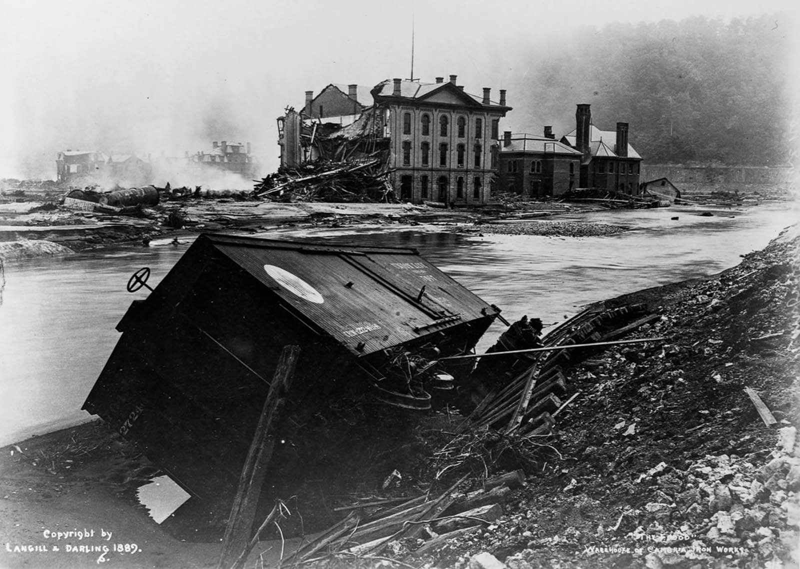 A freight car lies near the damaged Cambria Iron Works warehouse.
