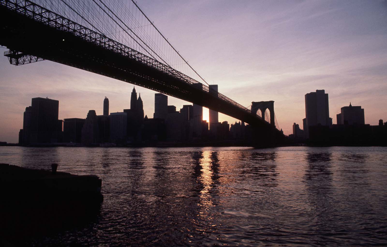 The Brooklyn Bridge and skyline of lower Manhattan remain dark as the sun sets.