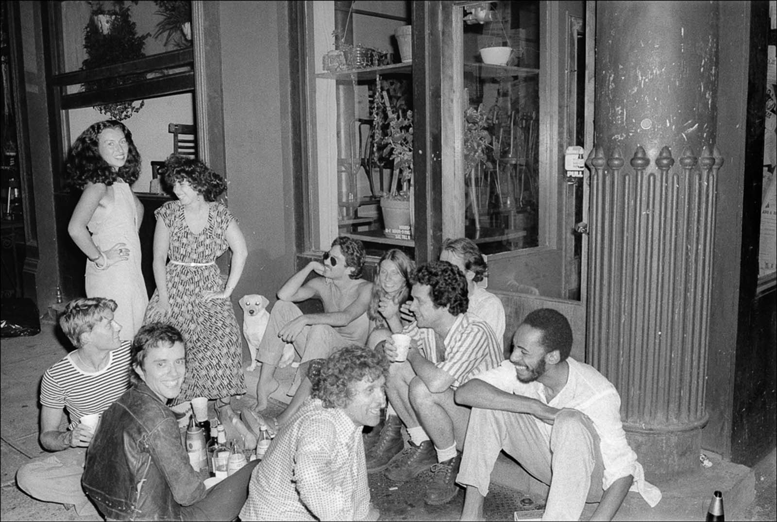 A group of people hold a party on a SoHo sidewalk.