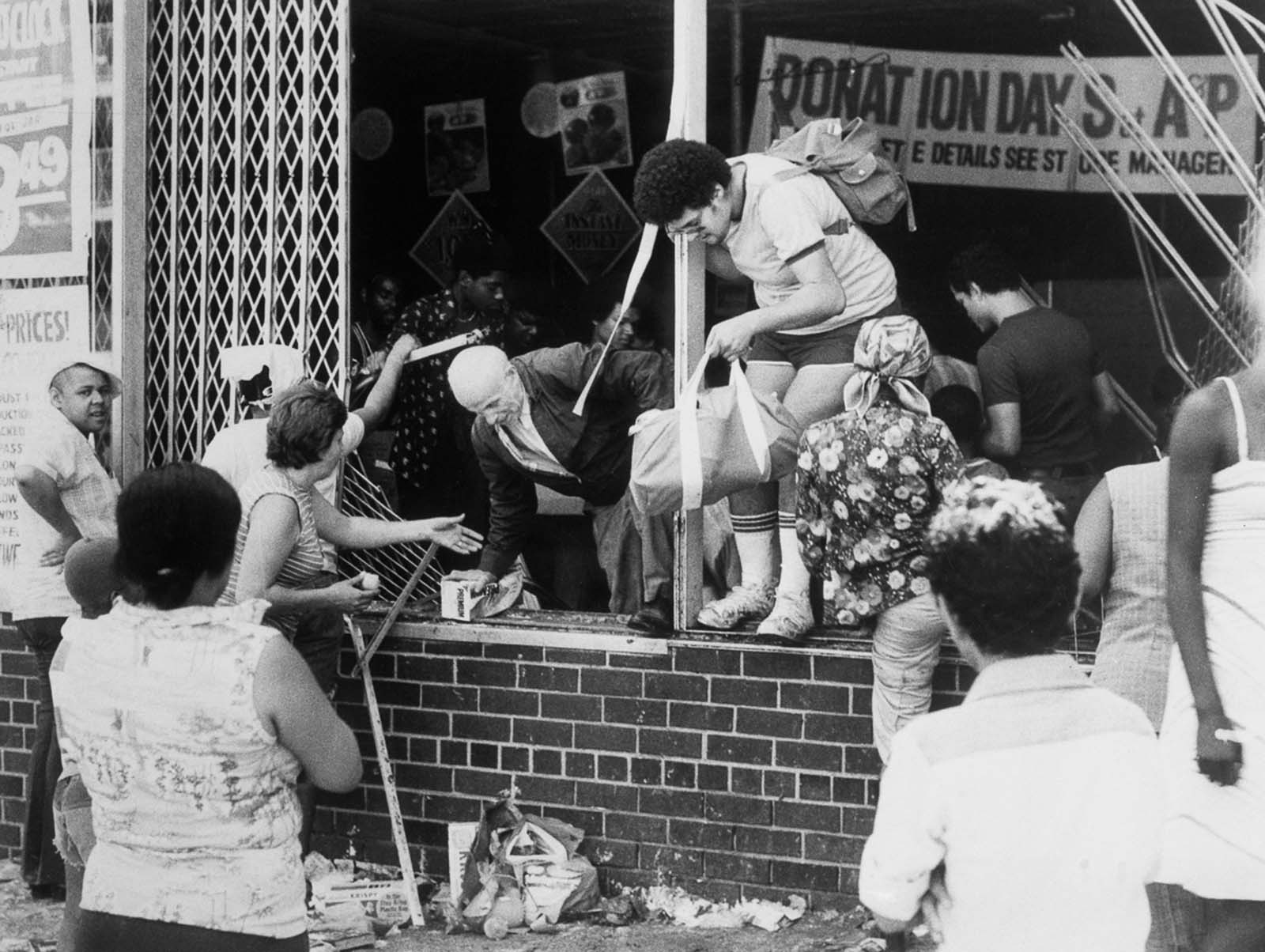 People carry looted goods out of an A&P supermarket at Ogden Avenue and 166th Street in the Bronx.