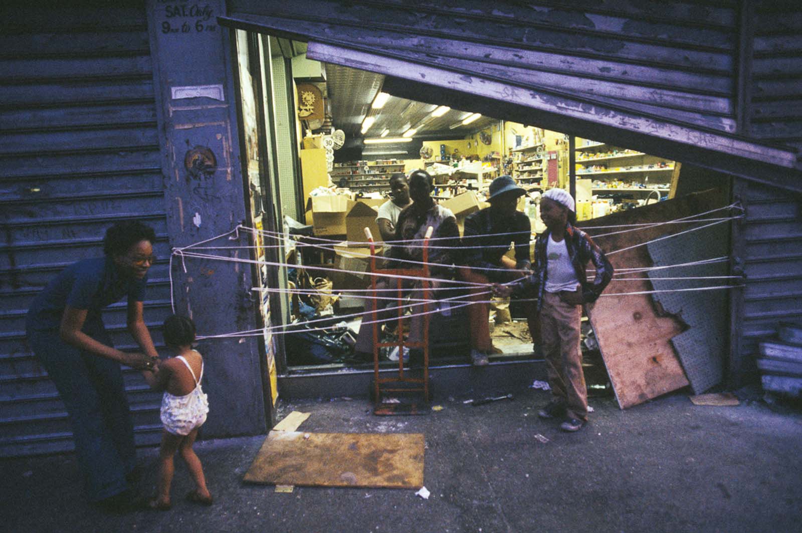 Store owners guard their damaged storefront against further looting.