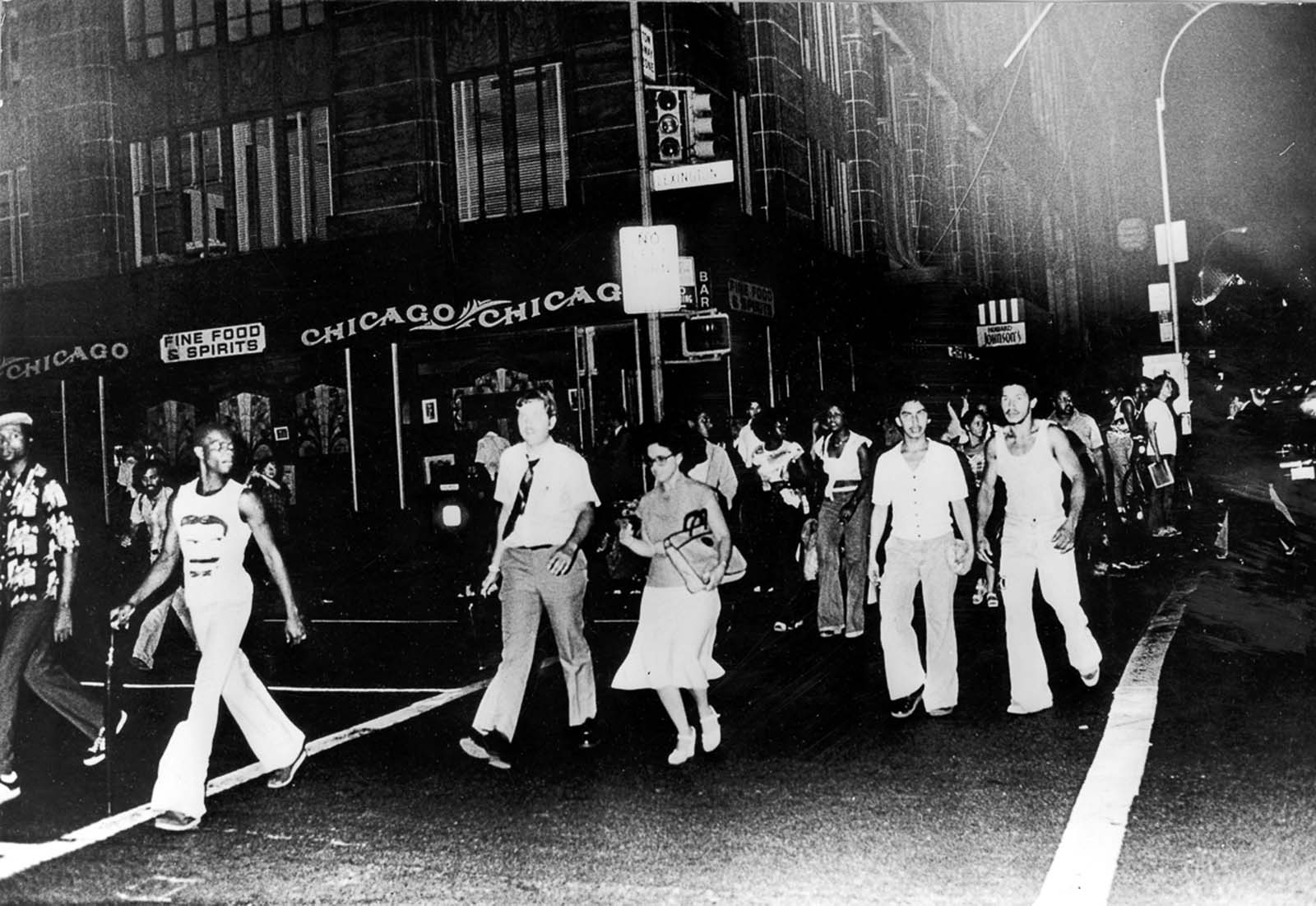 People cross Lexington Avenue in darkness.