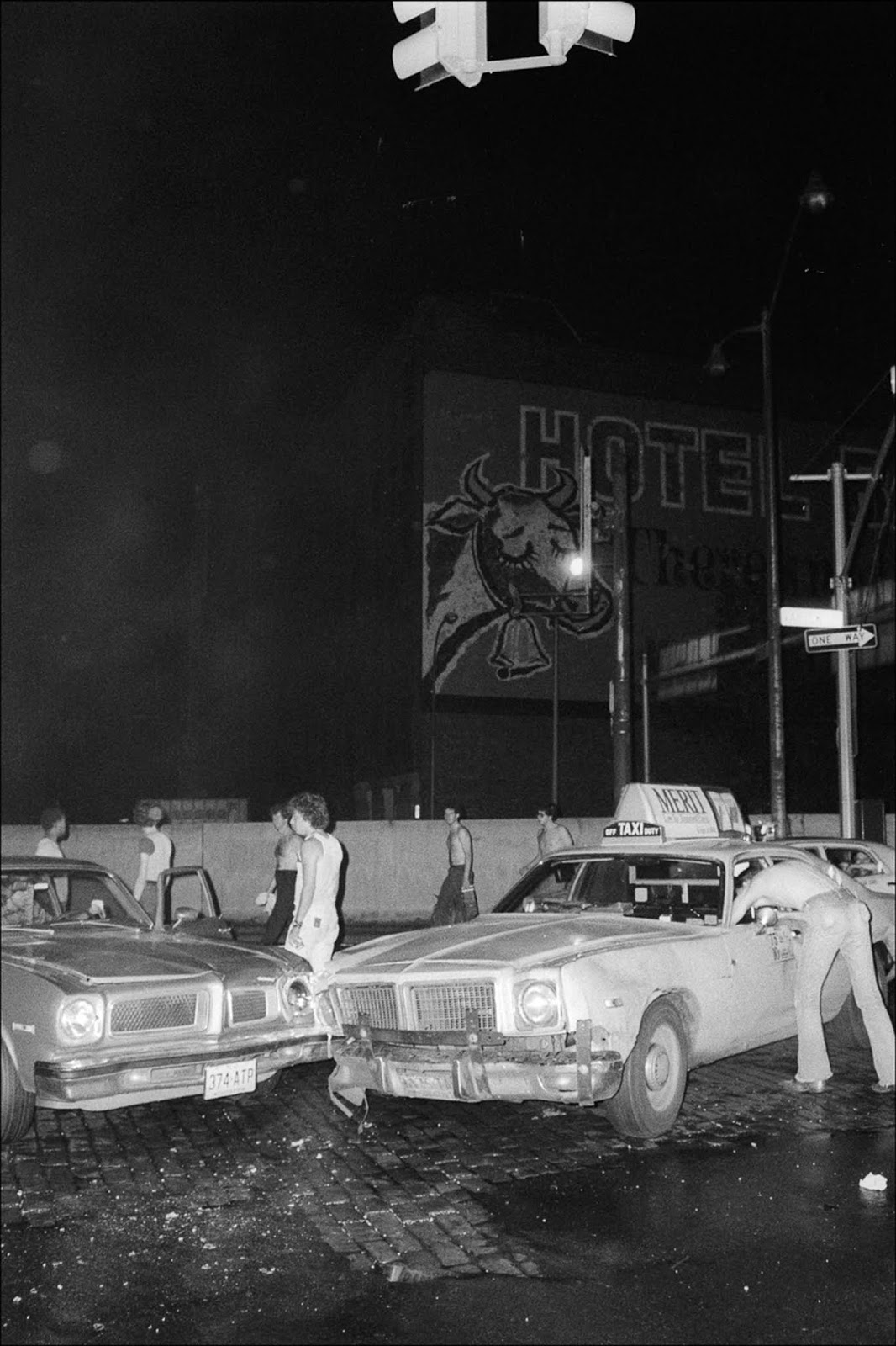 People gather around the site of a car crash in the dark.