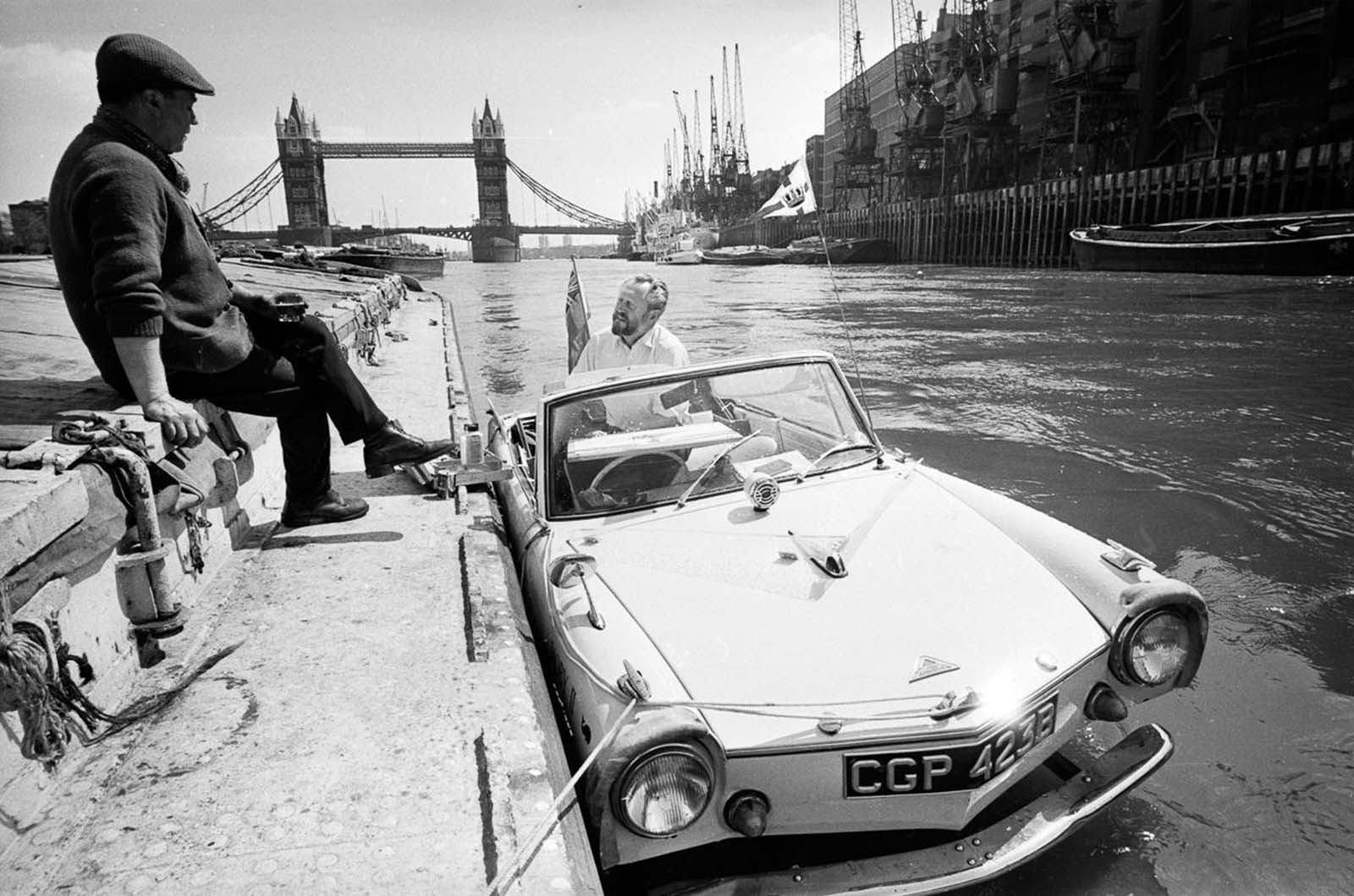 Artist John Worsley docks his Amphicar near Tower Bridge in London. 1966.
