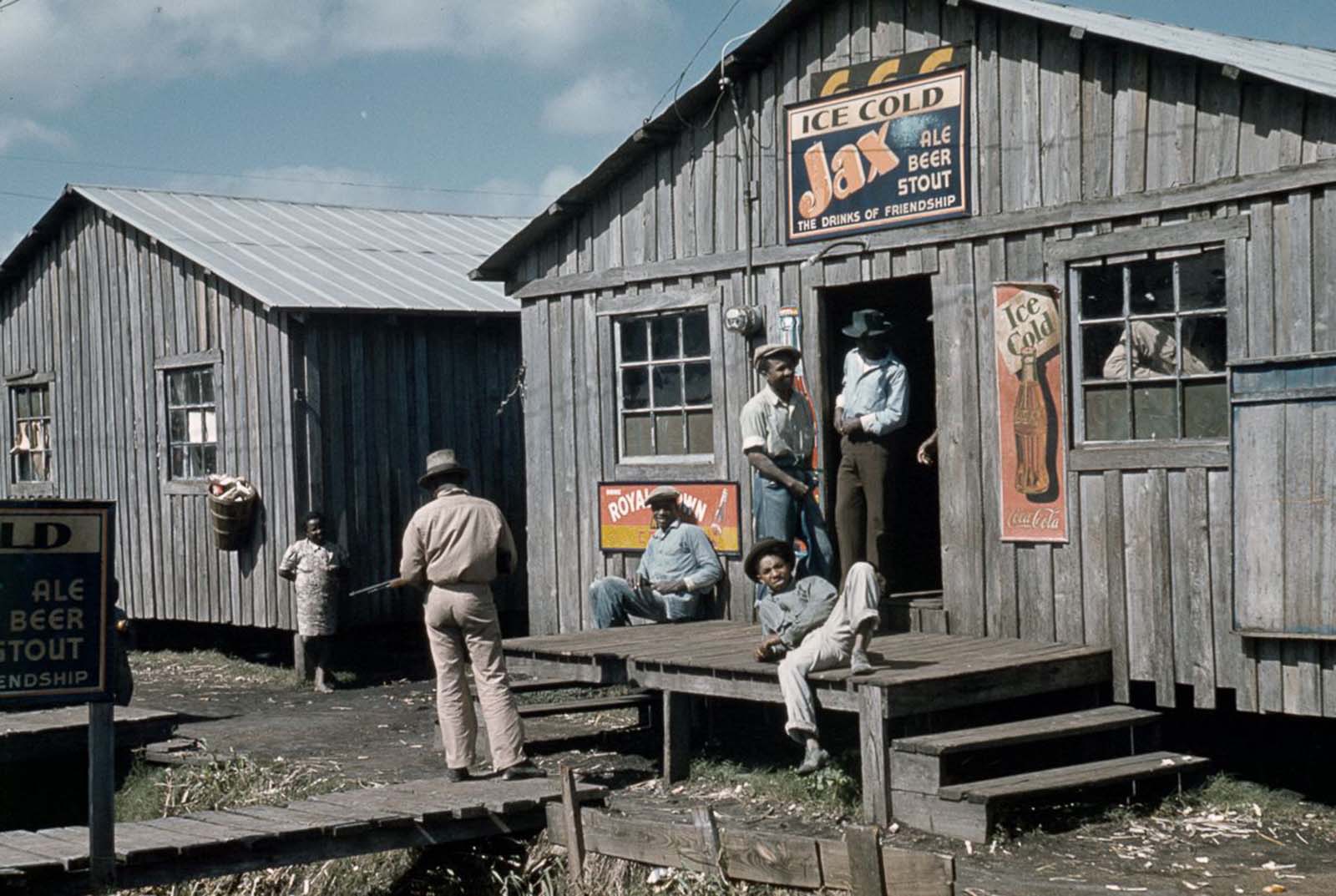 Migrant congregate outside a juke joint during a slack season in Belle Glade, Florida. 1941.