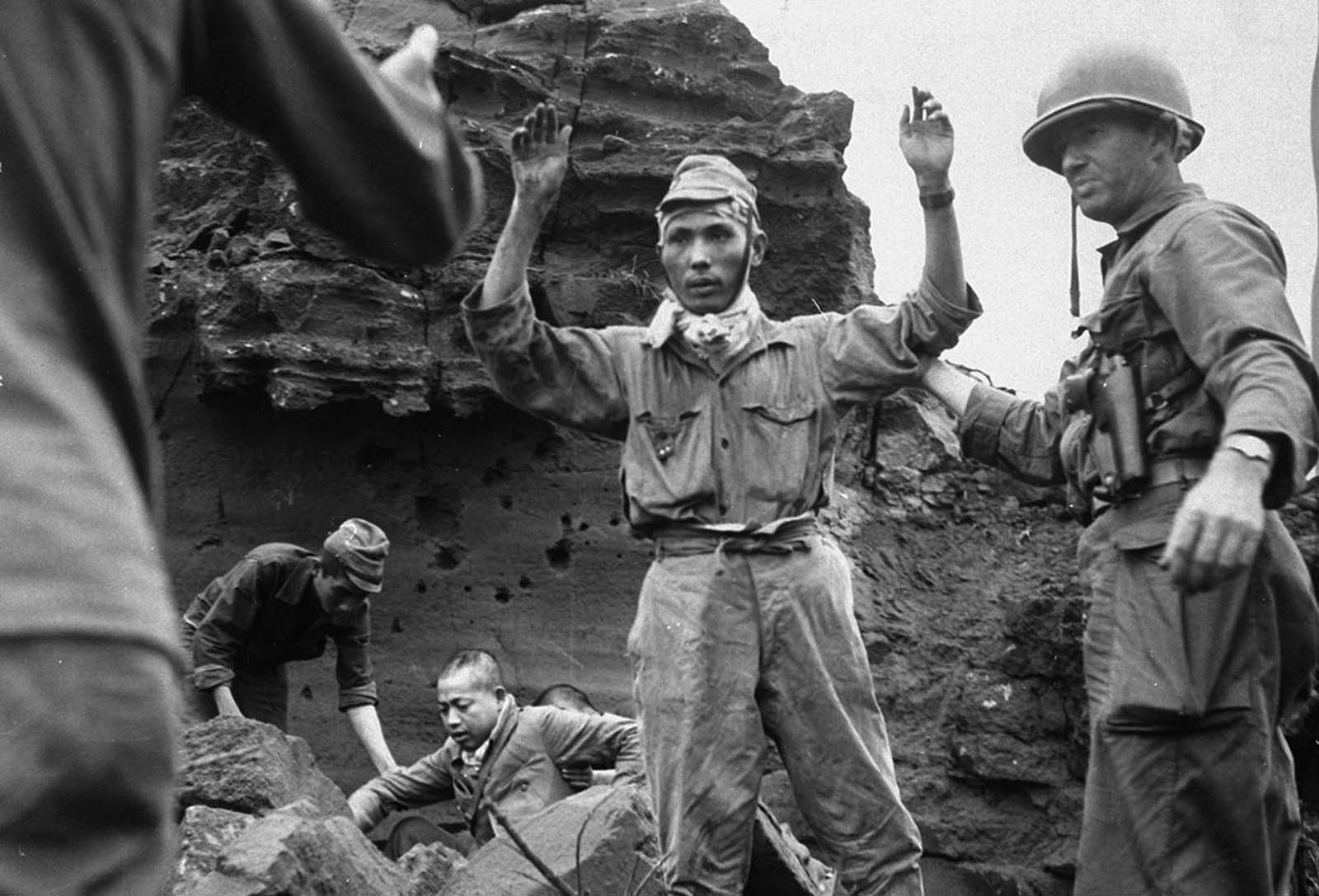 With his hands in the air, the first of 20 Japanese emerges from a cave on Iwo Jima, on April 5, 1945. The group had been hiding for several days.