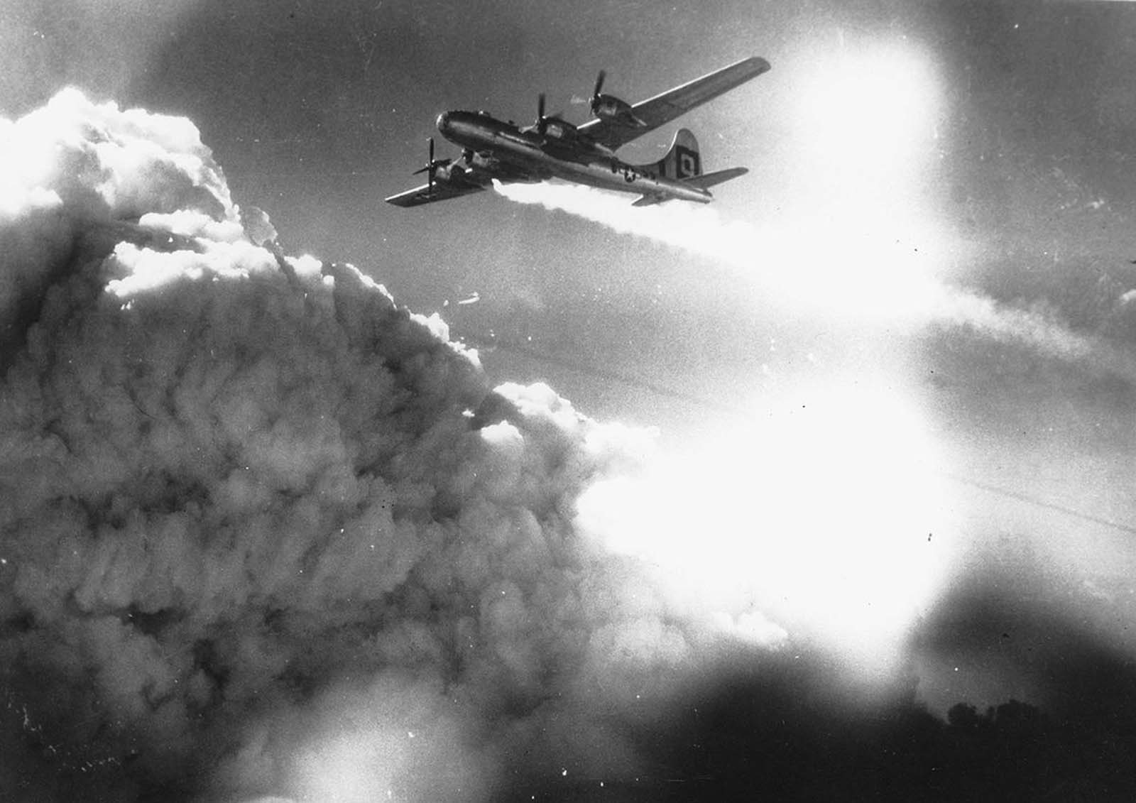 In flight over the Japanese city of Kobe, a U.S. Army Air Forces B-29 Superfortress trails smoke and fire, on July 17, 1945.