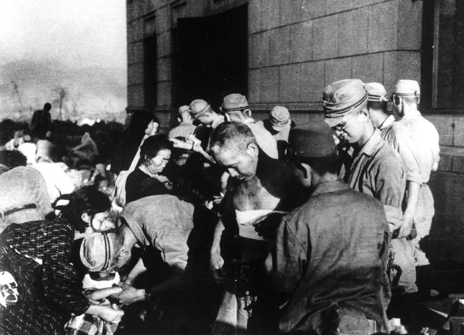 Hiroshima atomic bombing survivors receive emergency treatment by military medics, on August 6, 1945.