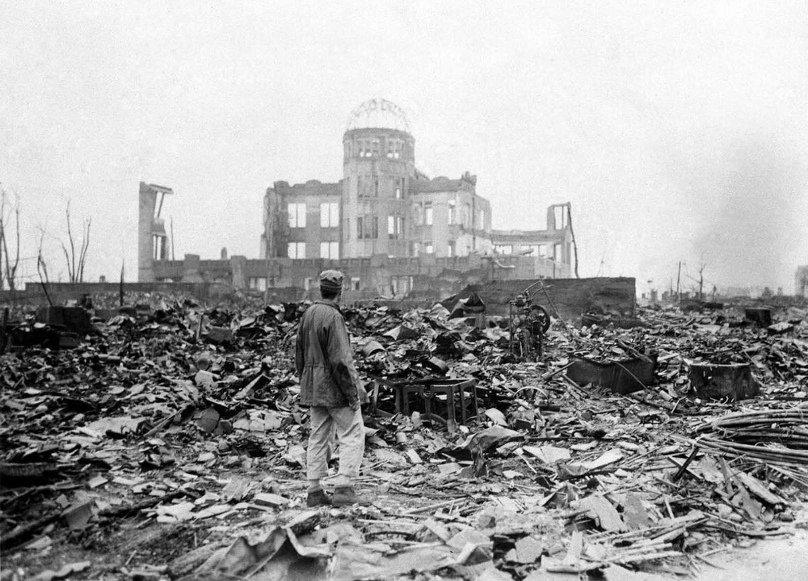 An allied correspondent stands in the radioactive rubble in front of the shell of a building that once was an exhibition hall in Hiroshima, Japan, one month after the first atomic bomb ever used in warfare was dropped on the city by the U.S. The explosion took place almost directly above the dome.