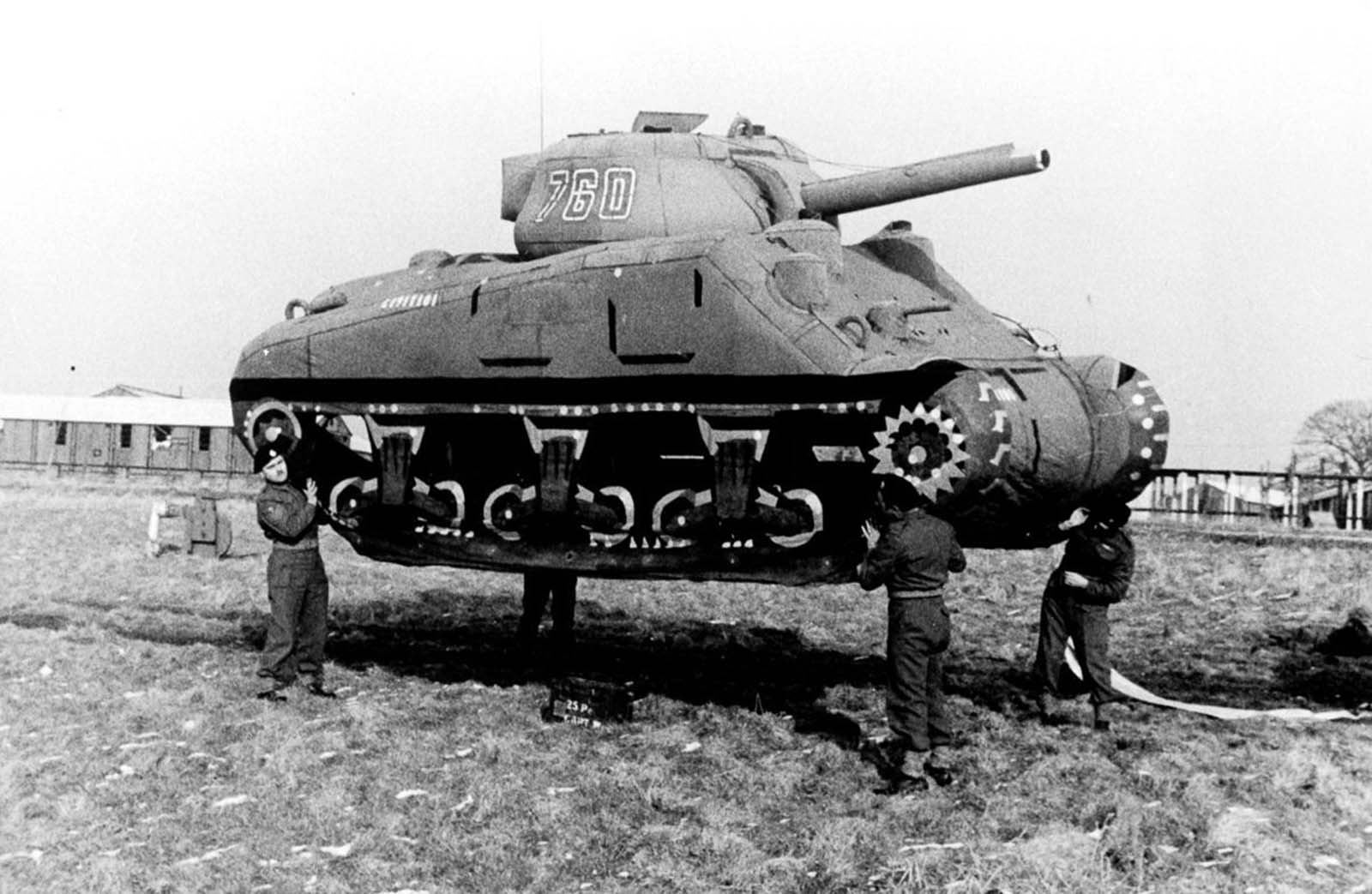 Soldiers lift up an inflatable rubber dummy tank in England. 1939.
