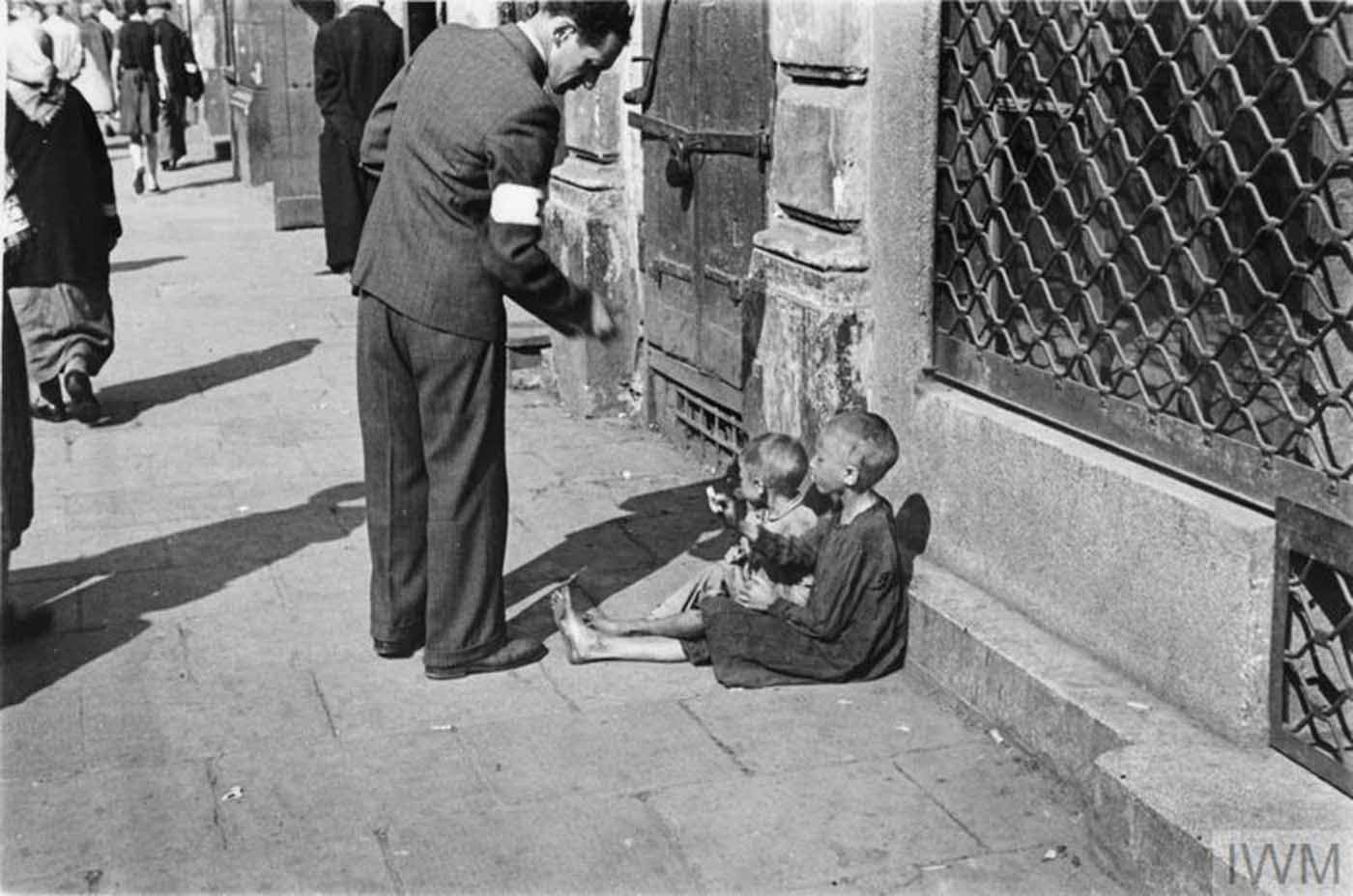 A passer-by giving money to two children. 