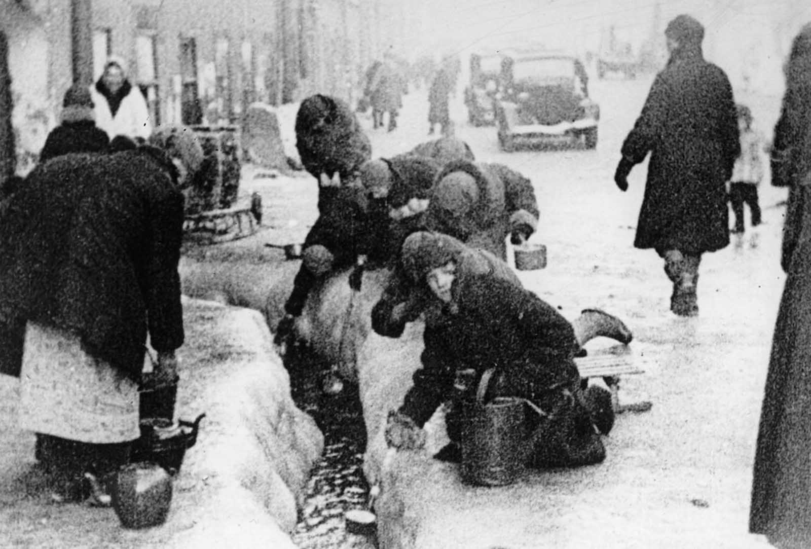 This photo, taken in the winter months of 1942, shows citizens of Leningrad as they dip for water from a broken main, during the nearly 900-day siege of the Russian city by German invaders. Unable to capture the Leningrad (today known as Saint Petersburg), the Germans cut it off from the world, disrupting utilities and shelling the city heavily for more than two years.