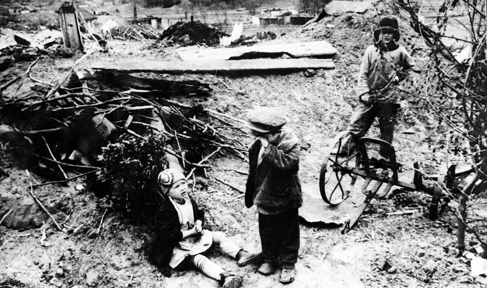 Three Russian war orphans stand amid the remains of what was once their home, in late 1942. After German forces destroyed the family's house, they took the parents as prisoners, leaving the children abandoned.
