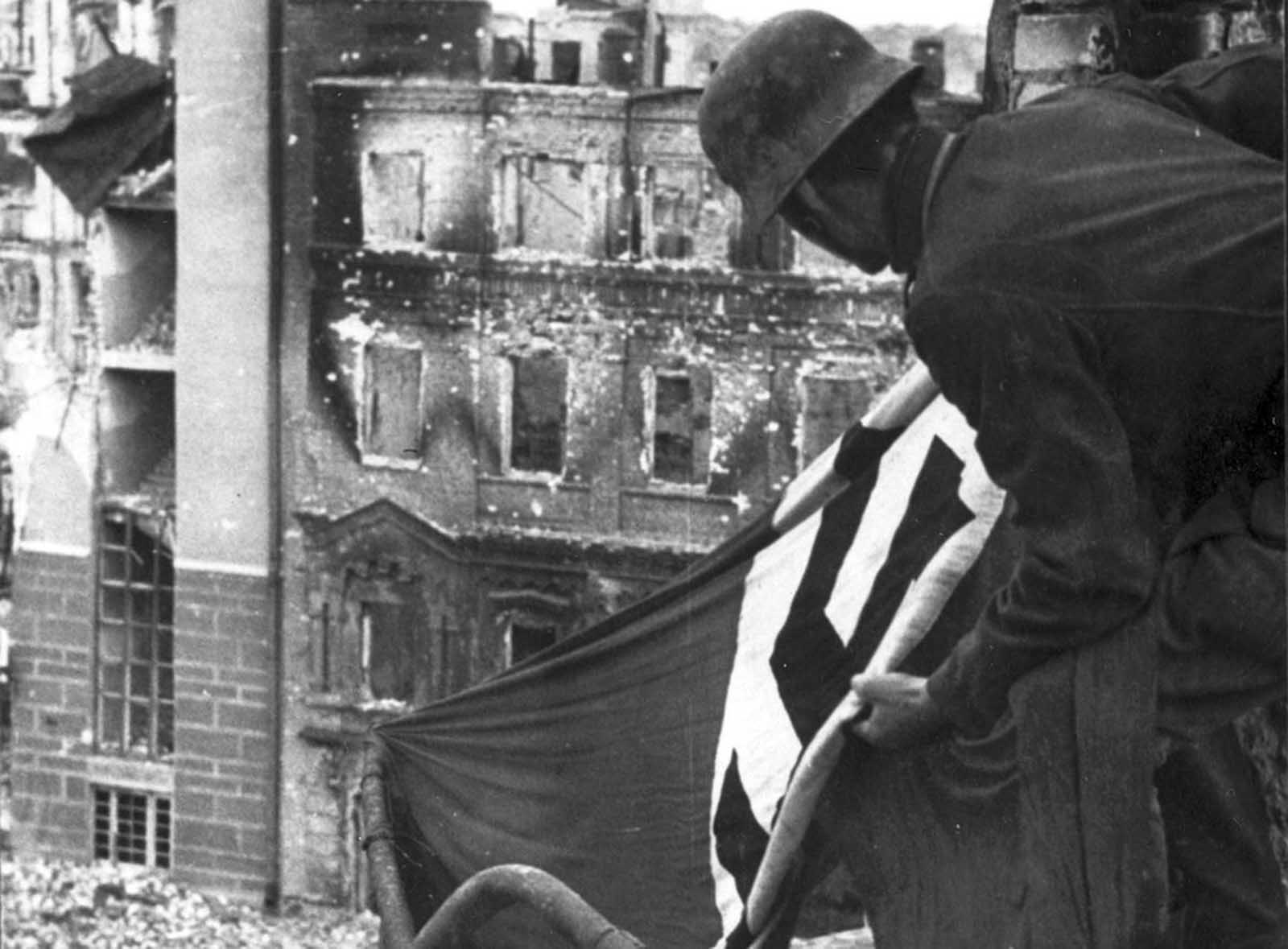 Sometime in the Autumn 1942, a German soldier hangs a Nazi flag from a building in downtown Stalingrad.