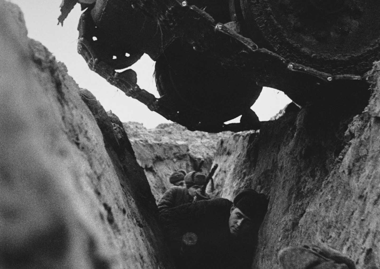 Red Army soldiers in a trench as a Russian T-34 tank passes over them in 1943, during the Battle of Kursk.