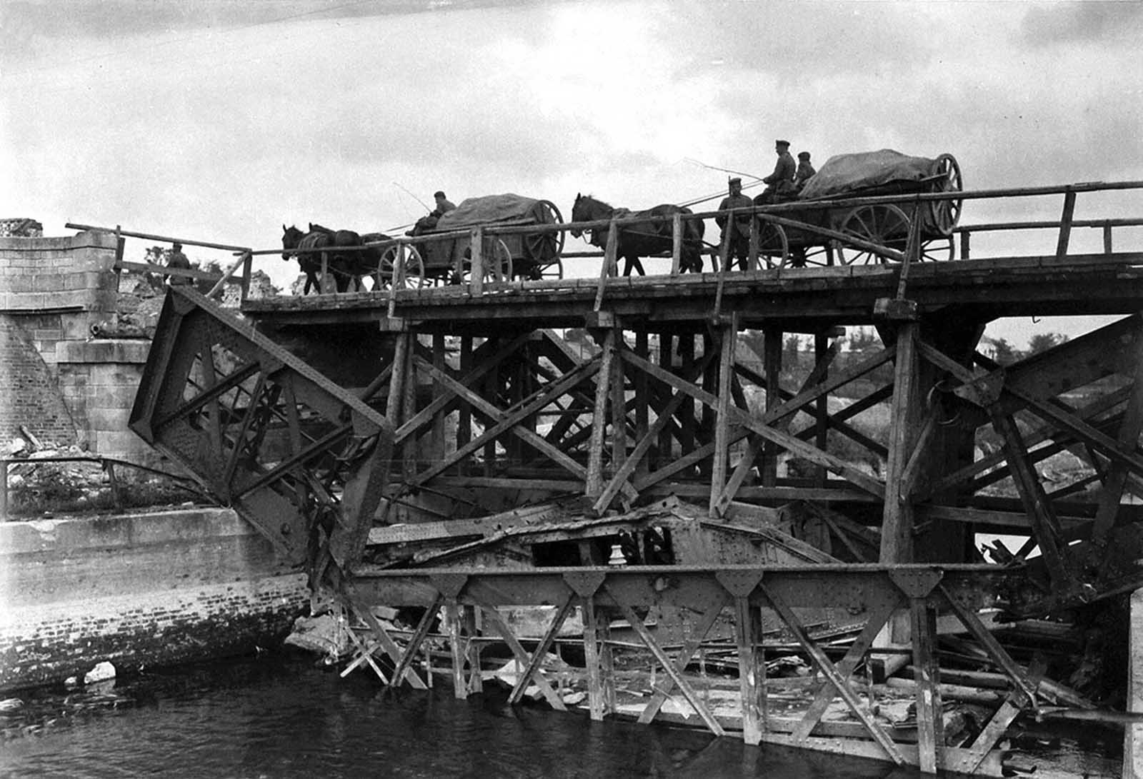 On the site where a steel bridge was destroyed, a wooden temporary bridge has been built in place. Note that an English tank which fell in the river when the former bridge was demolished now serves as part of the foundation for the new bridge over the Scheldt at Masnieres.