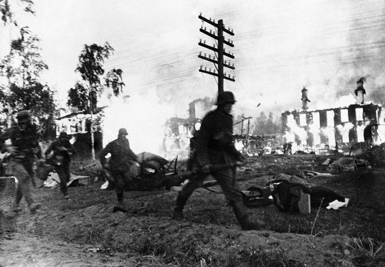 German troops make a hasty advance through a blazing Leningrad suburb, in Russia on November 24, 1941.